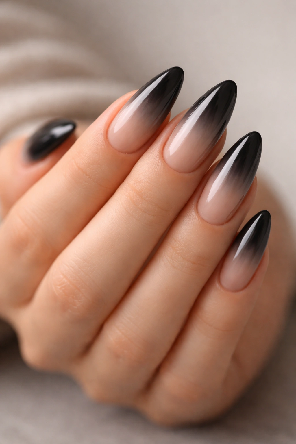 Close-up of black smoke ombre almond nails from nude to black