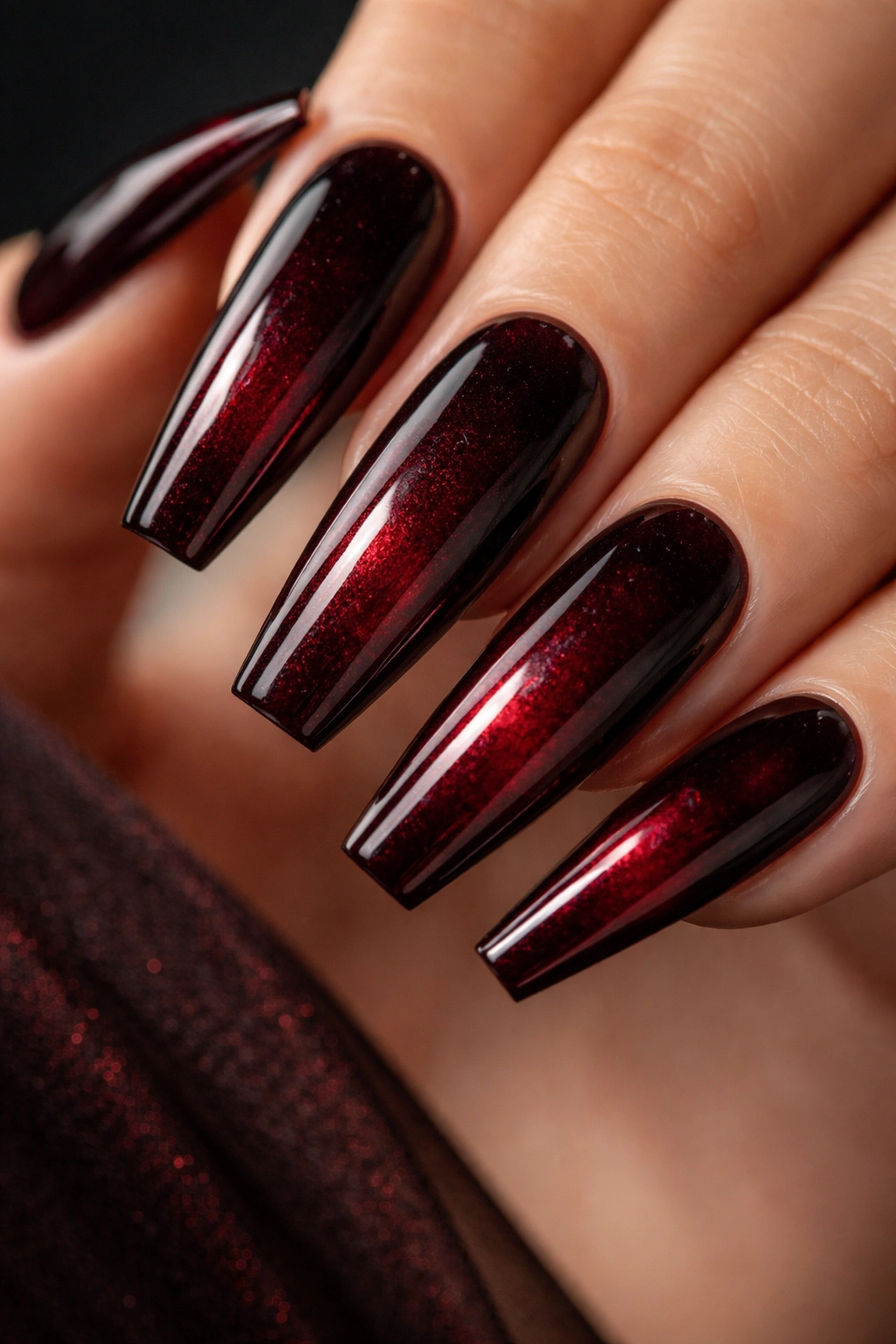 Close-up of coffin nails painted in dark ruby with glossy finish