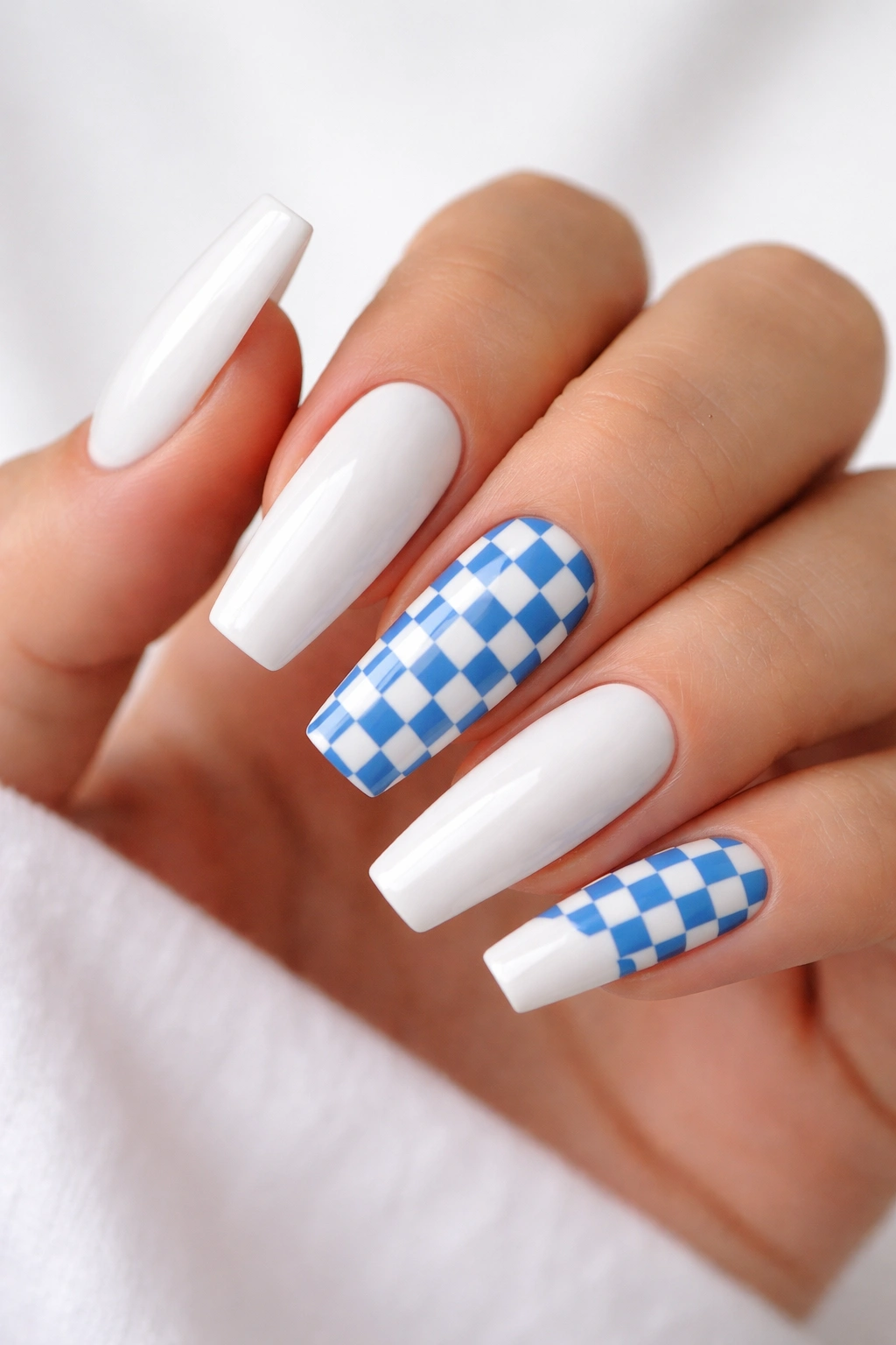Close-up of coffin nails with blue checkerboard accents on a white base.