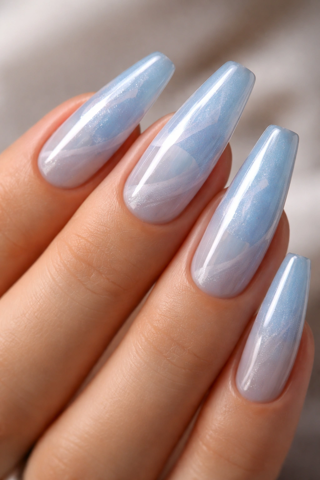 Close-up of milky blue coffin nails on a hand with subtle translucency and marbling.