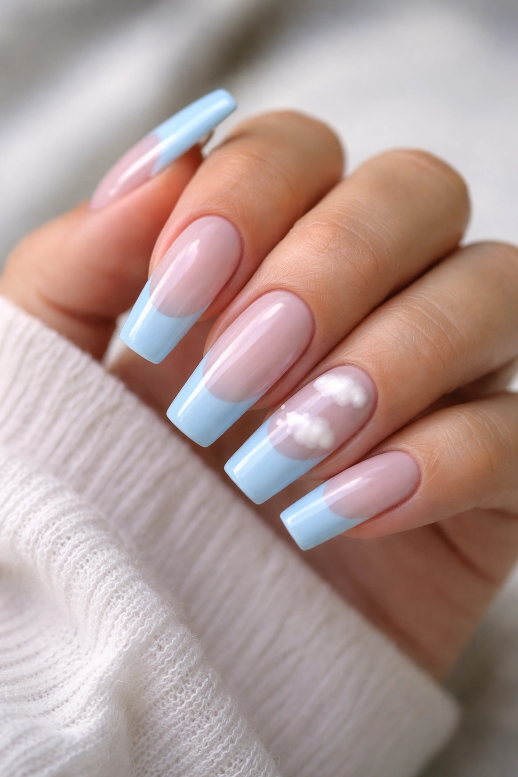 Close-up of light blue French tips with tiny white cloud accents on sky-blue base.