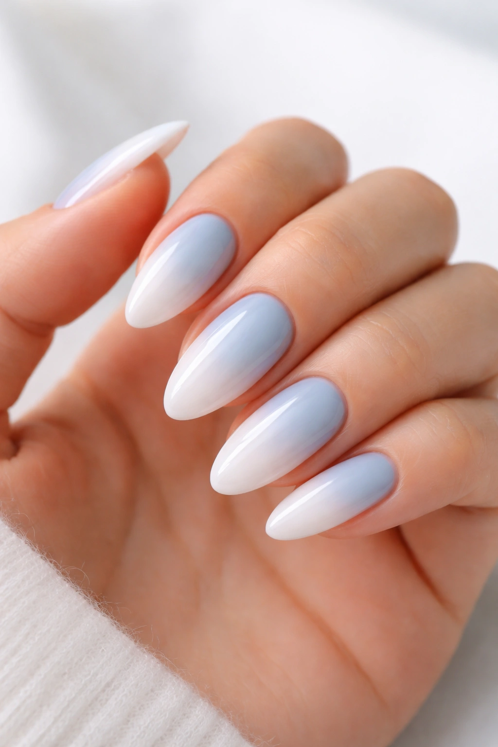 Close-up baby blue to white drift almond nails with sponge fade