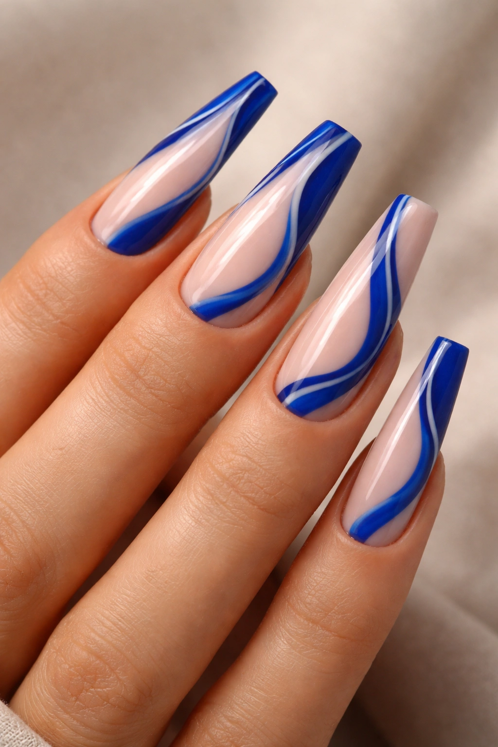 Close-up of true blue swirl coffin nails showing asymmetrical blue lines on a nude base.