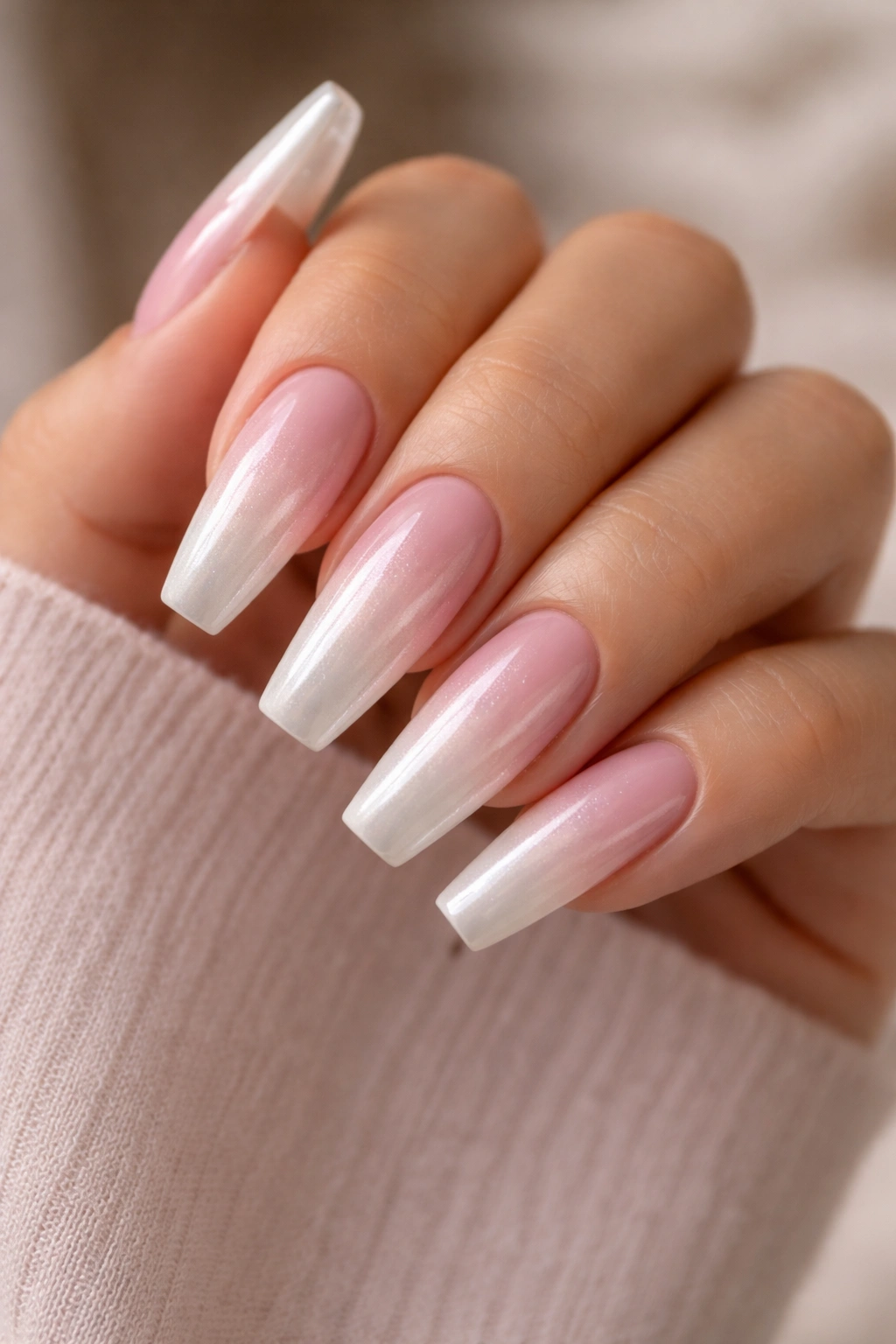 Blush ombré coffin nails with pearl chrome on a hand