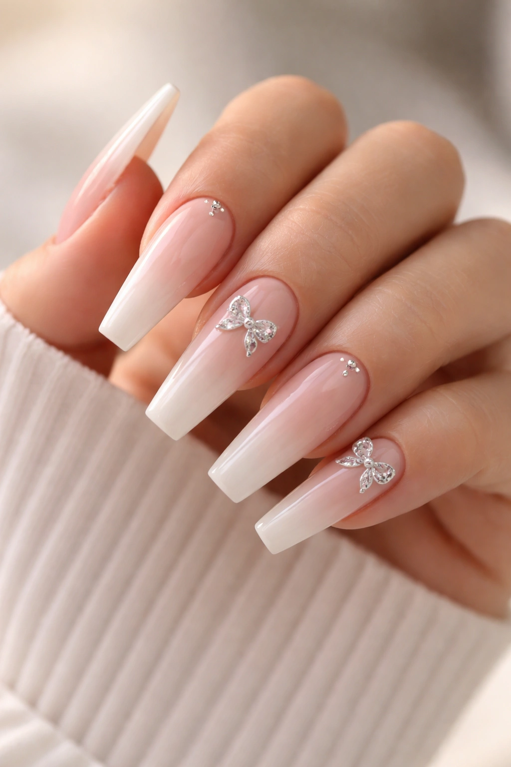 Close-up of tapered coffin nails with subtle bow details on a neutral hand