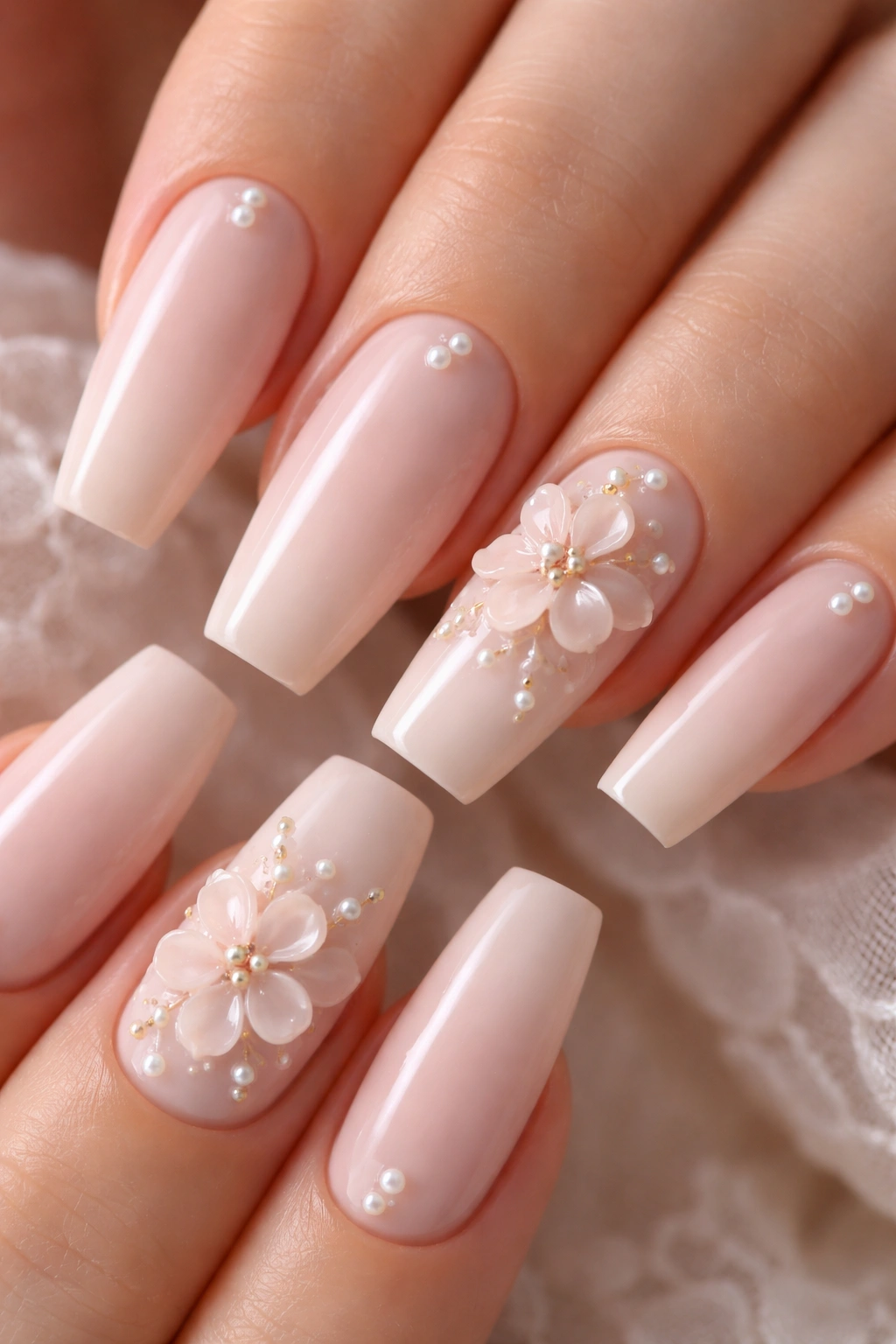 Close-up of blush-pink coffin nails with tiny pearls and blush flowers.
