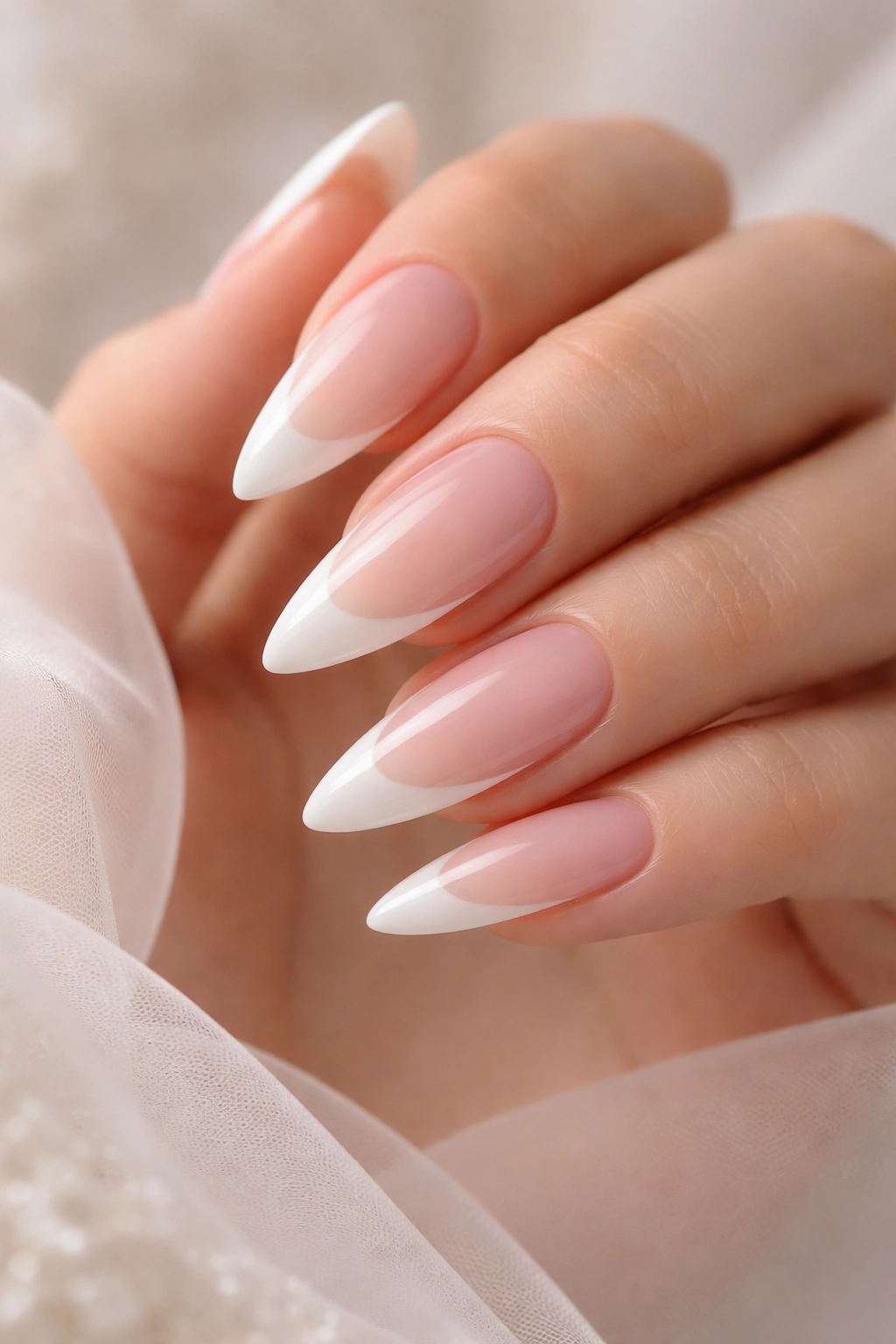 Close-up of long almond nails with sheer pink base and soft milky white tip, bridal French manicure.