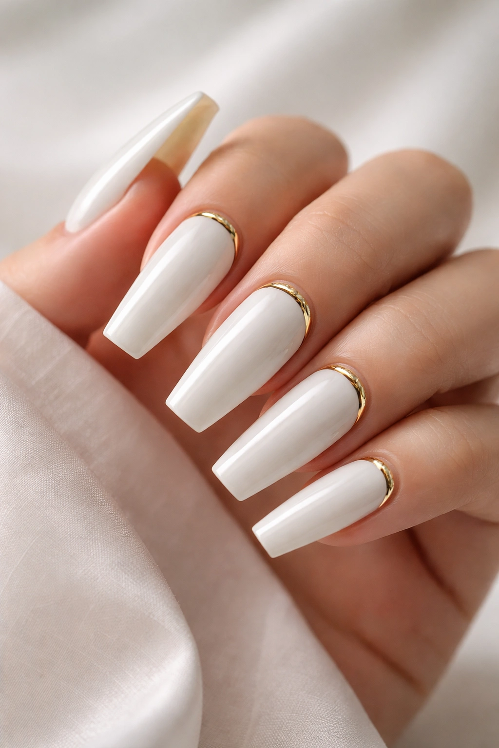 Close-up of bridal white coffin nails with gold cuff accents near the cuticle