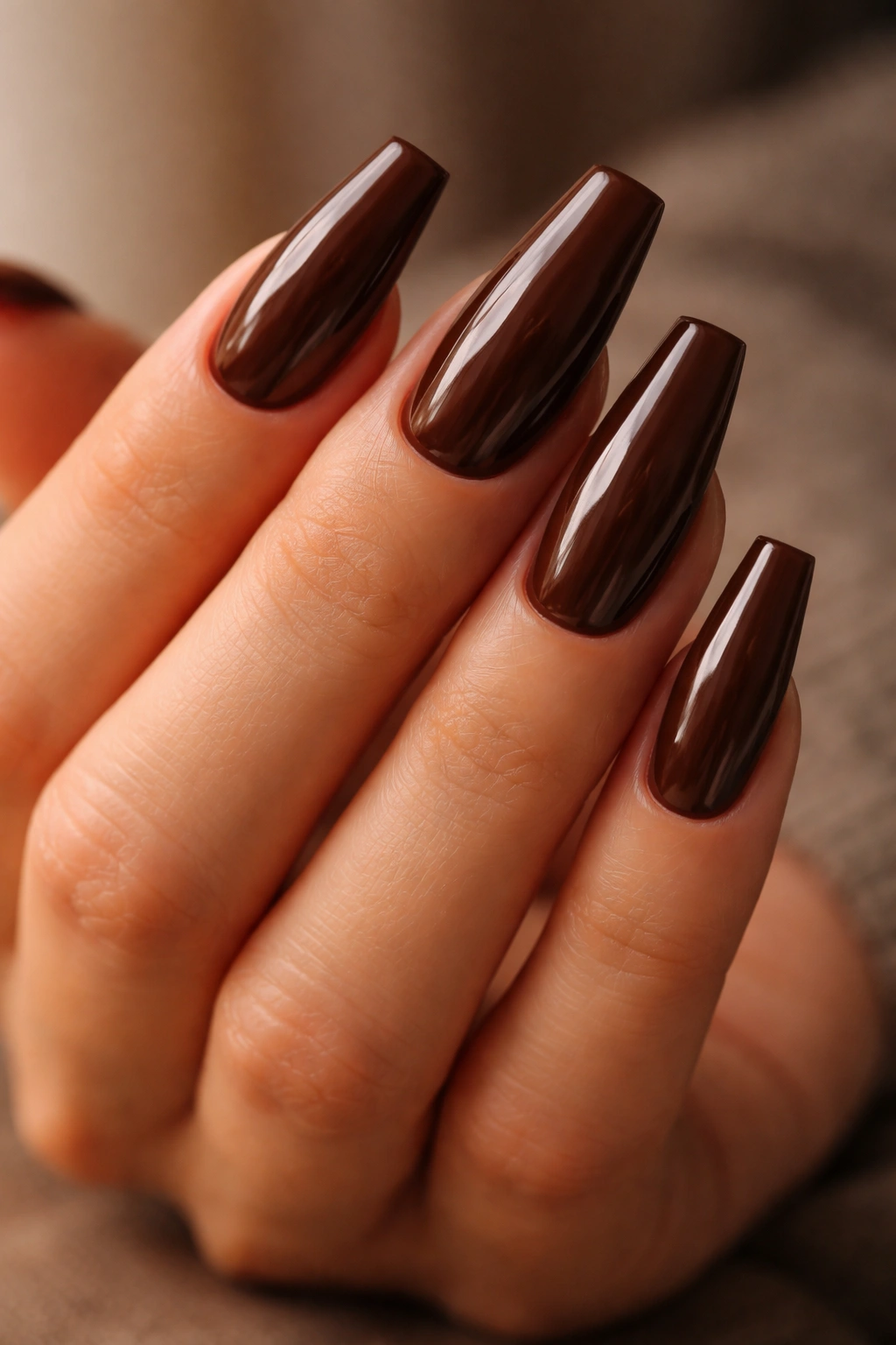 Close-up of medium-length brown coffin nails with espresso gloss on a tapered shape