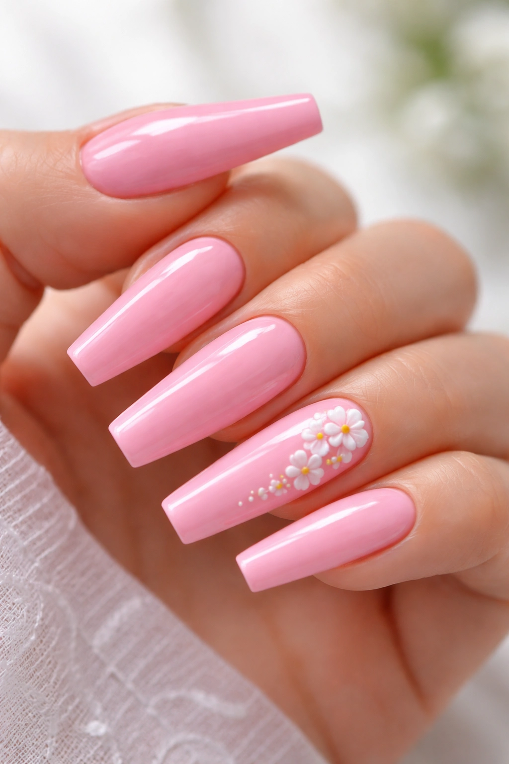 Close-up of bubblegum pink coffin nails with small white flower accent