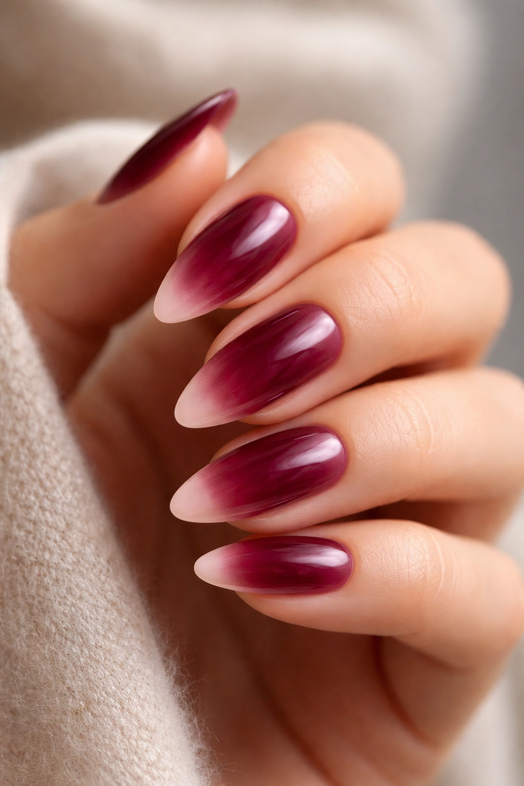 Burgundy aura nails on almond tips with soft glow gradient
