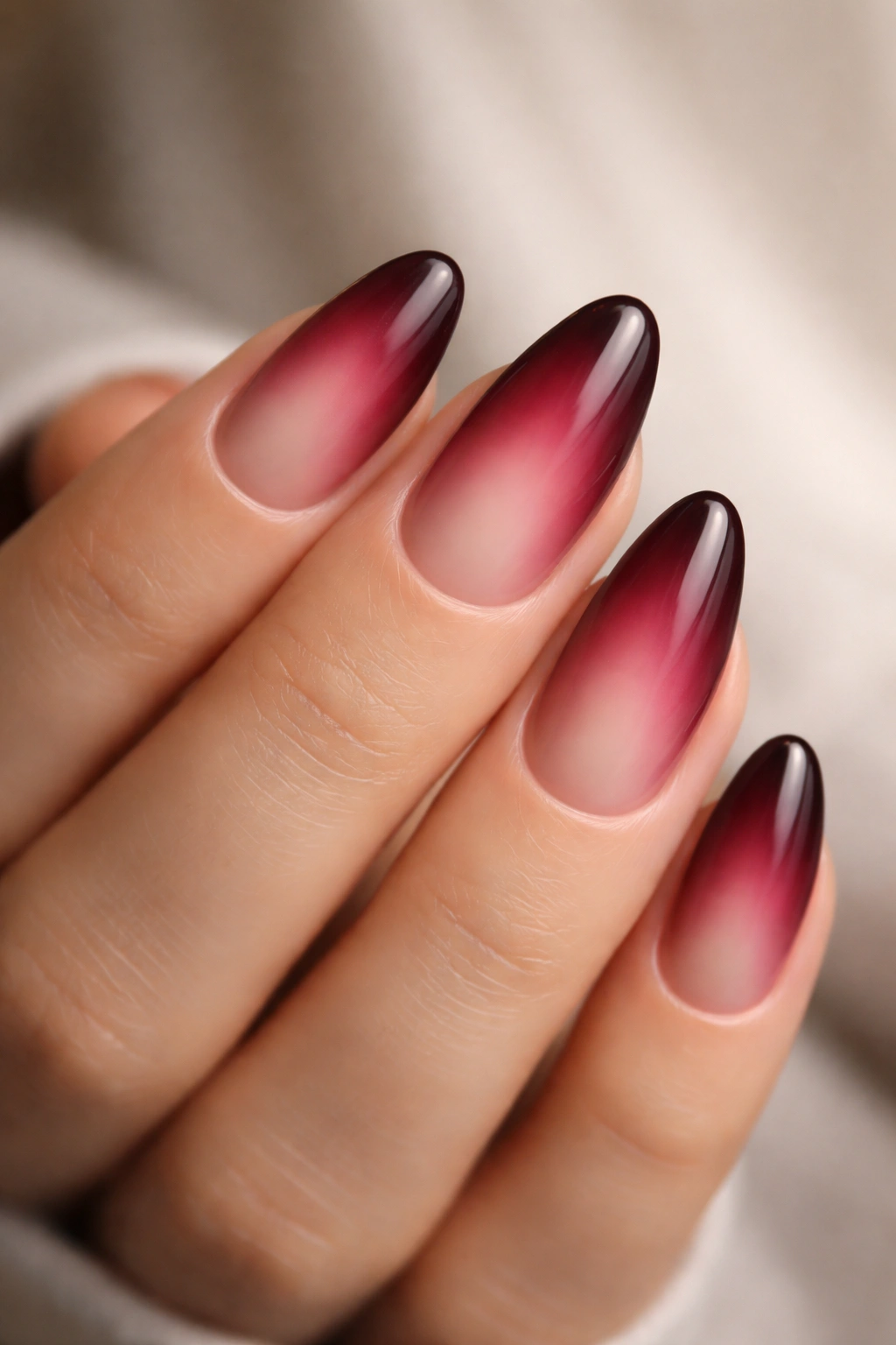 Almond nails featuring a burgundy aura with a soft glow and diffused center.