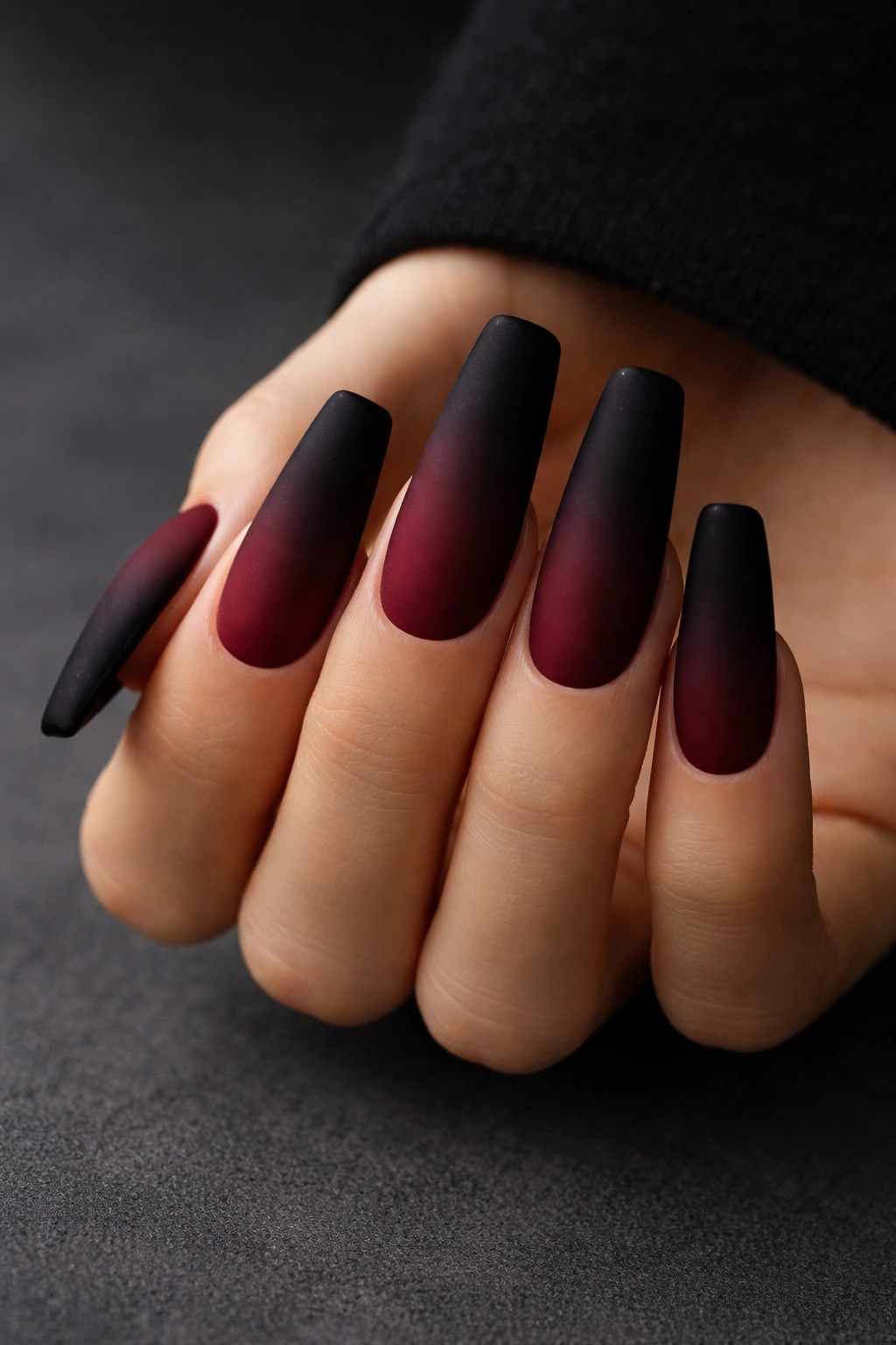 Close-up burgundy to black velvet ombre coffin nails with matte finish