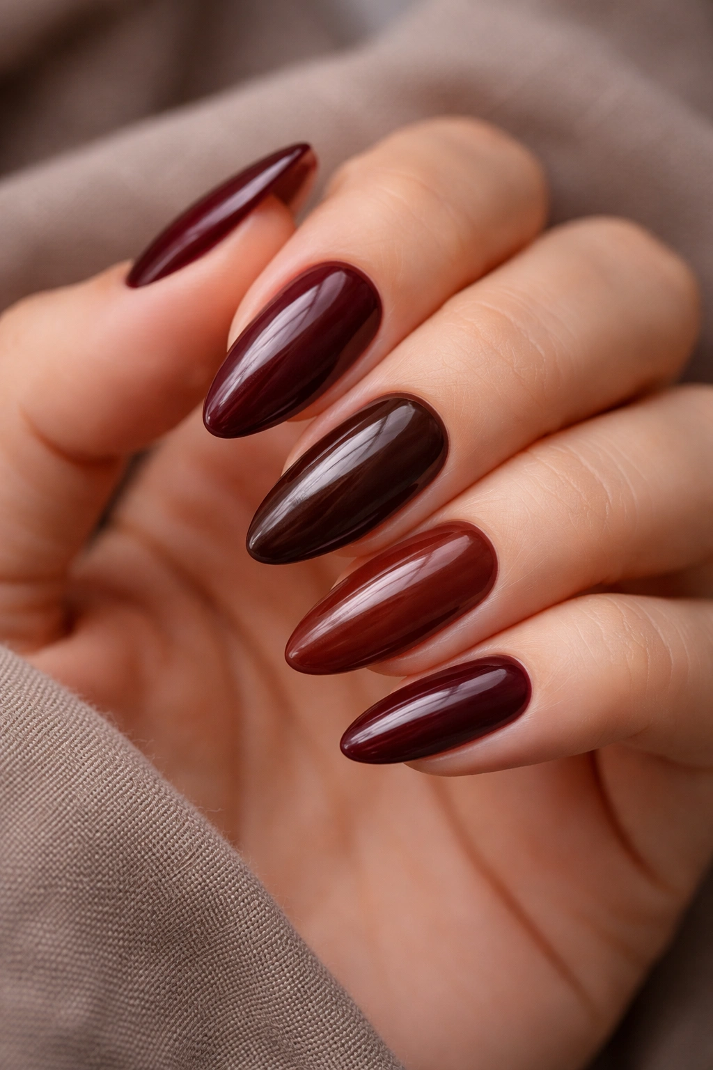 Almond nails in a tonal burgundy-brown palette with cohesive shading.