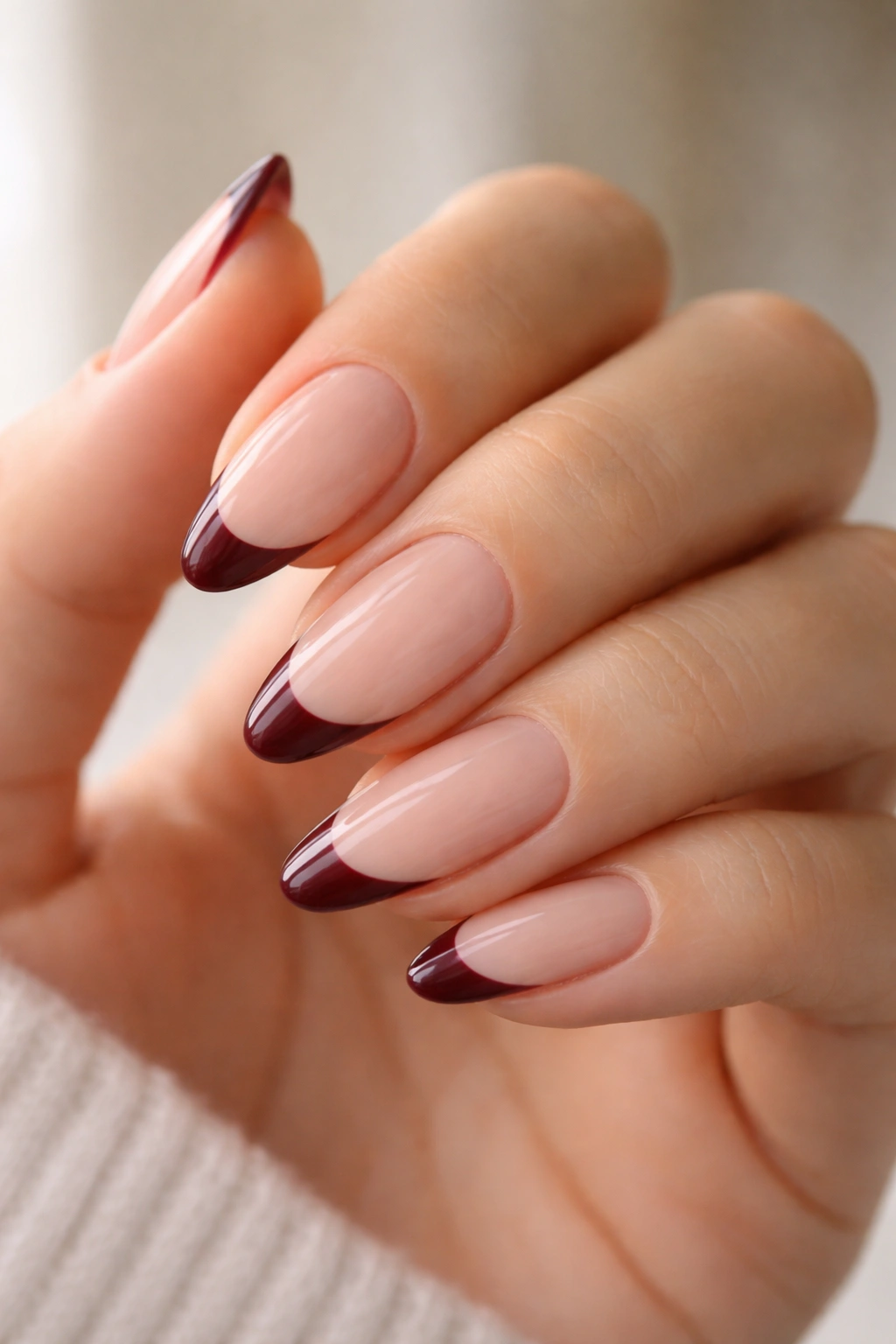Almond nails with sheer nude base and burgundy French tips