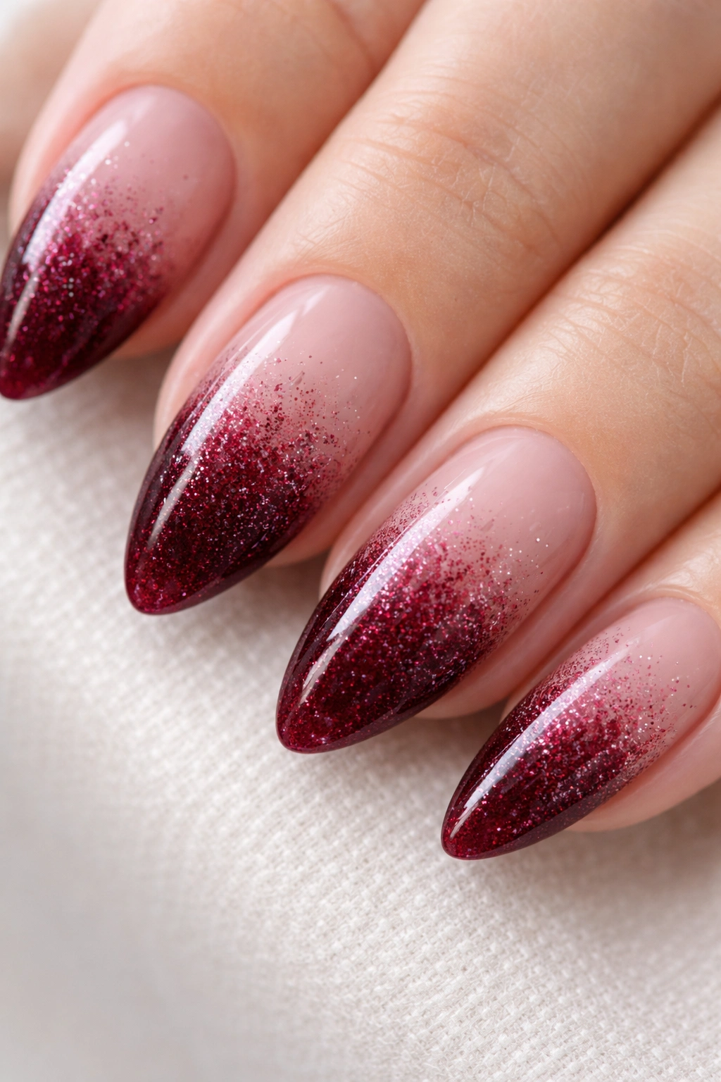 Almond nails with burgundy gradient and fine glitter fade at the tips.
