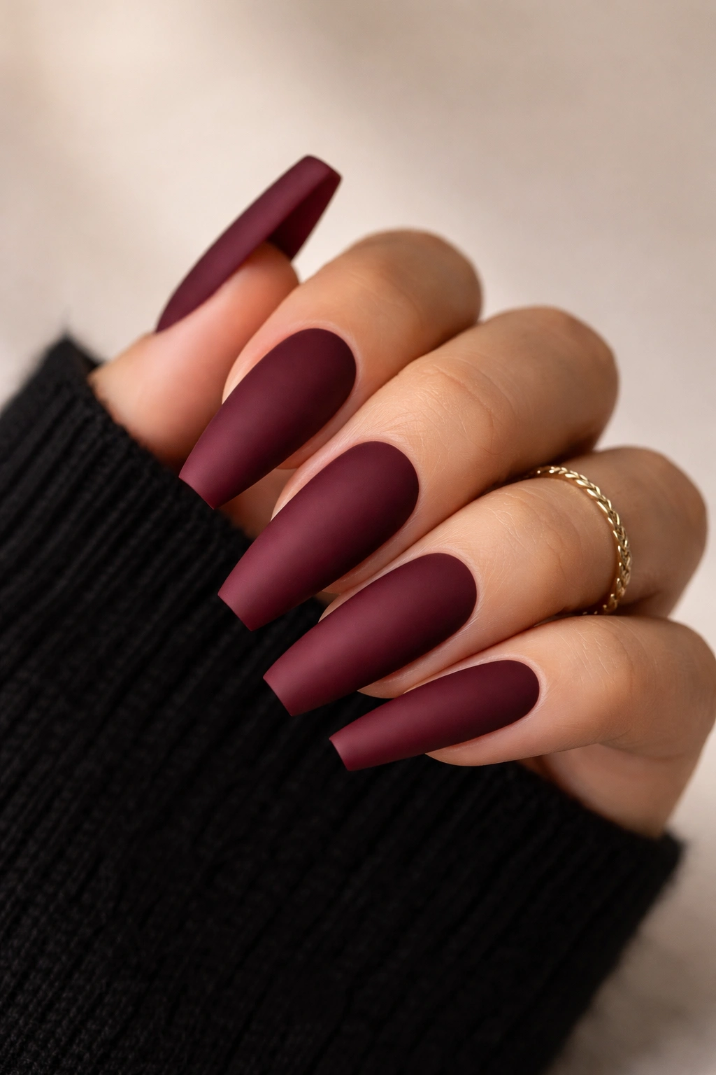 Close-up of burgundy matte coffin nails on a tapered shape with a clean neutral background