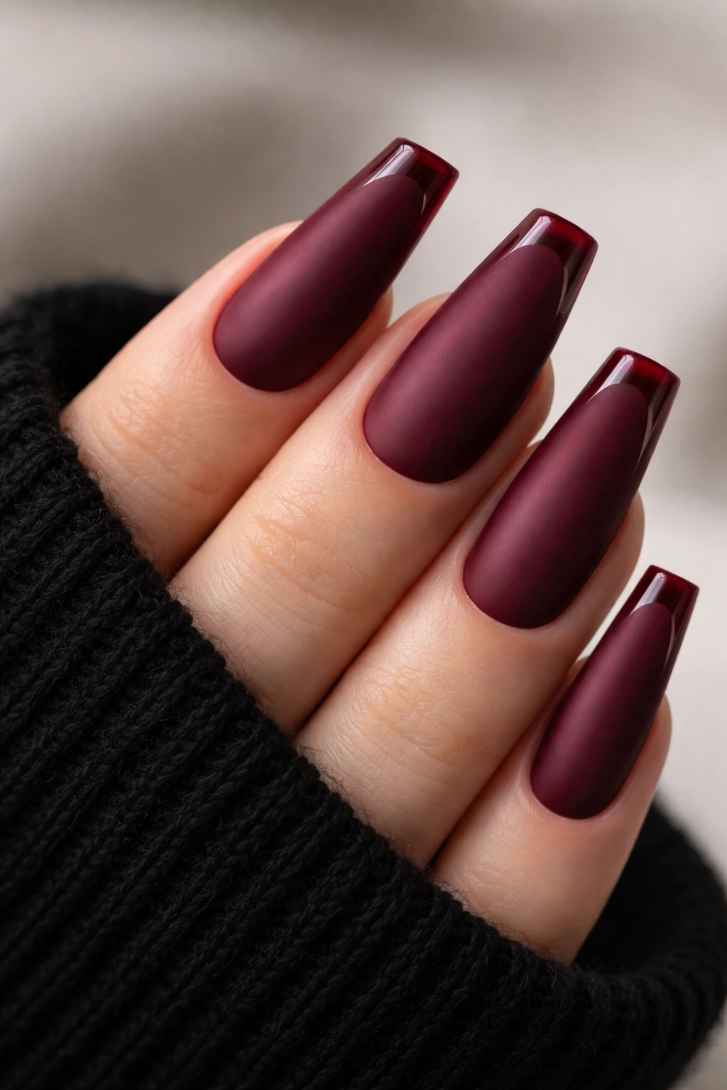 Close-up of burgundy matte coffin nails with glossy French tips