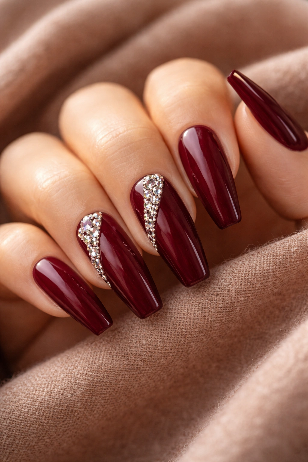Deep burgundy coffin nails with a diagonal sweep of gems