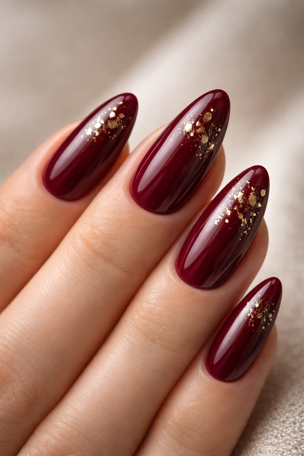 Burgundy almond nails with gold foil flecks