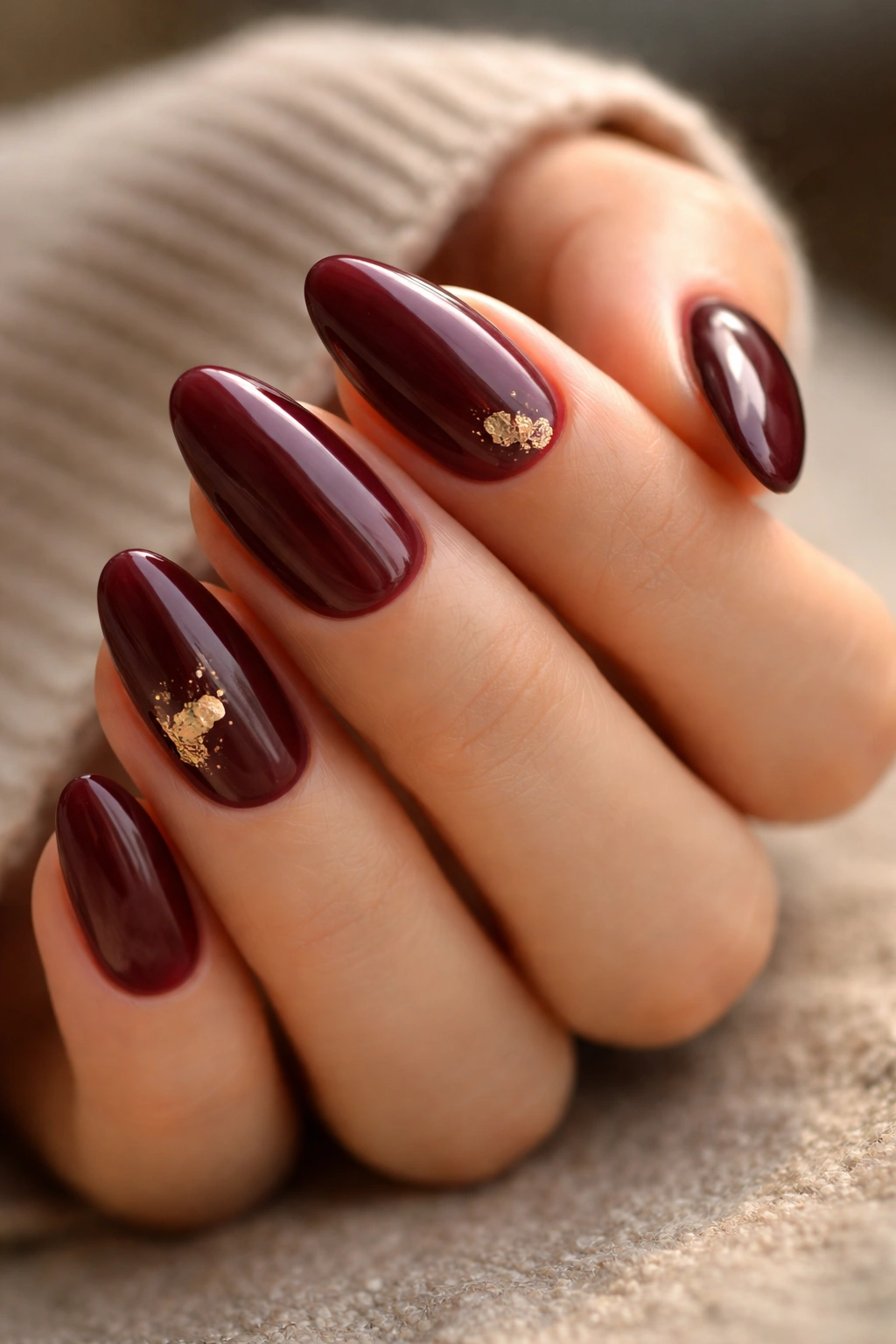 Burgundy nails with small gold foil accents on one or two nails