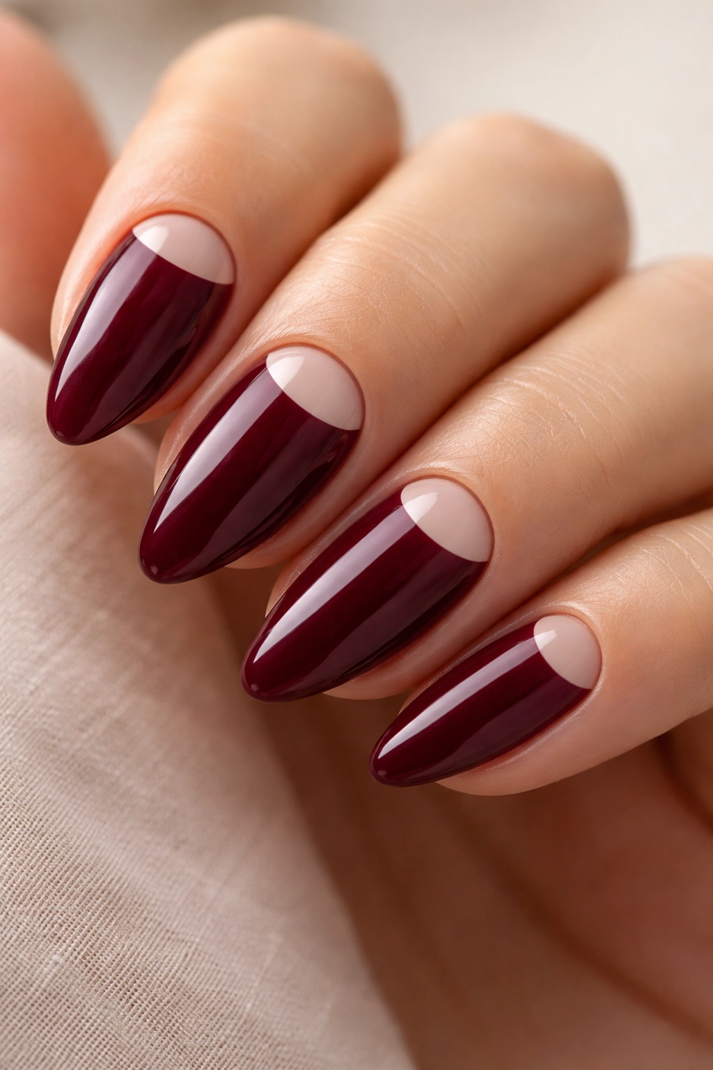Close-up of burgundy nails with a clear half-moon near the cuticle