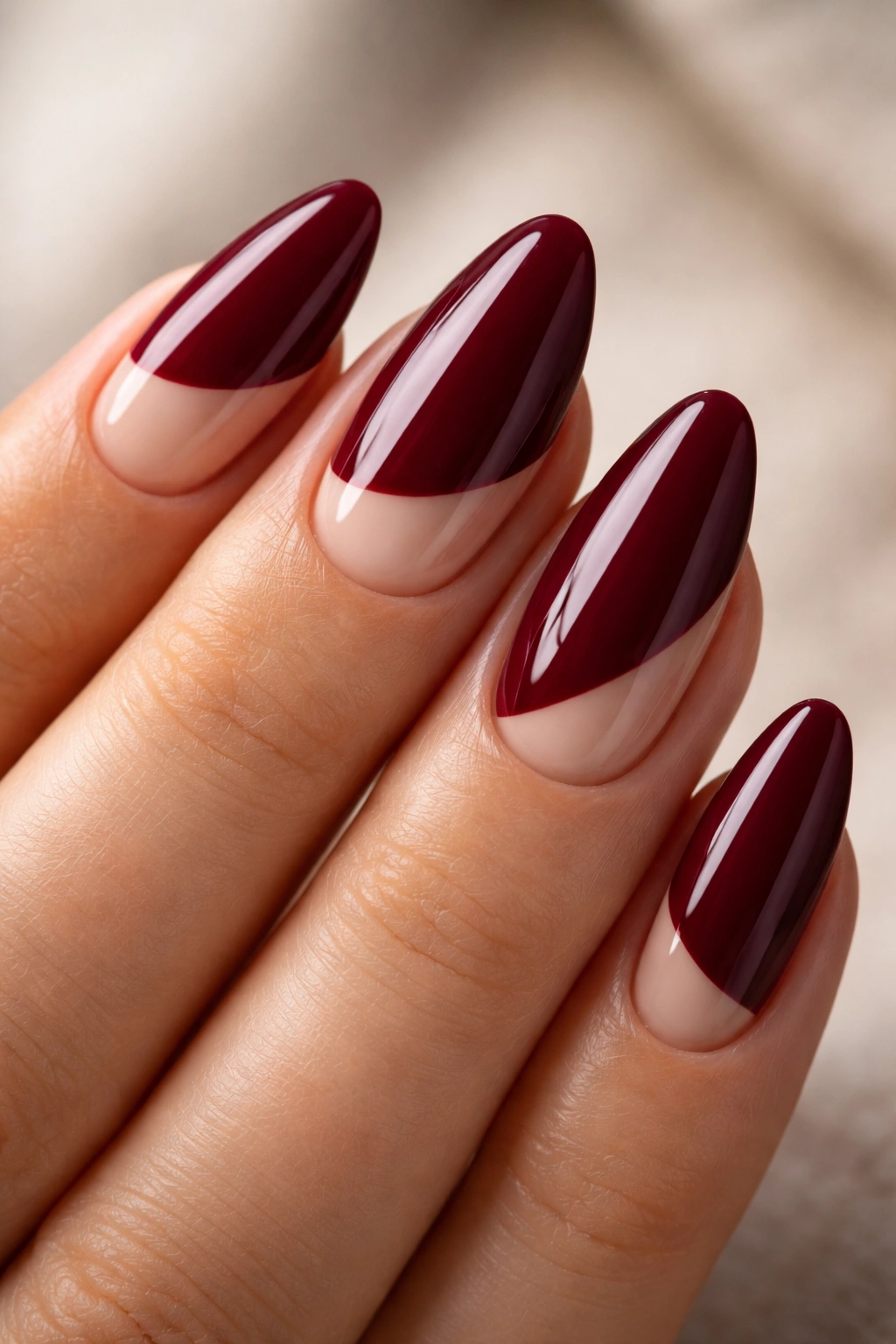 Close-up of burgundy almond nail with nude negative space cutout
