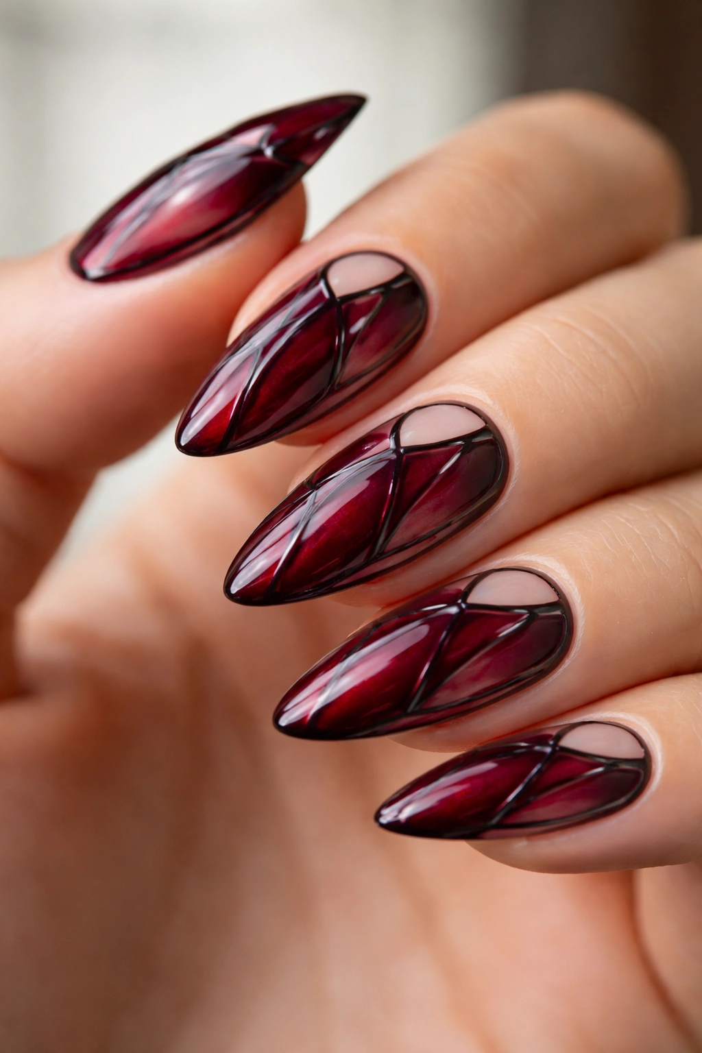 Almond nails with burgundy stained-glass panel design.