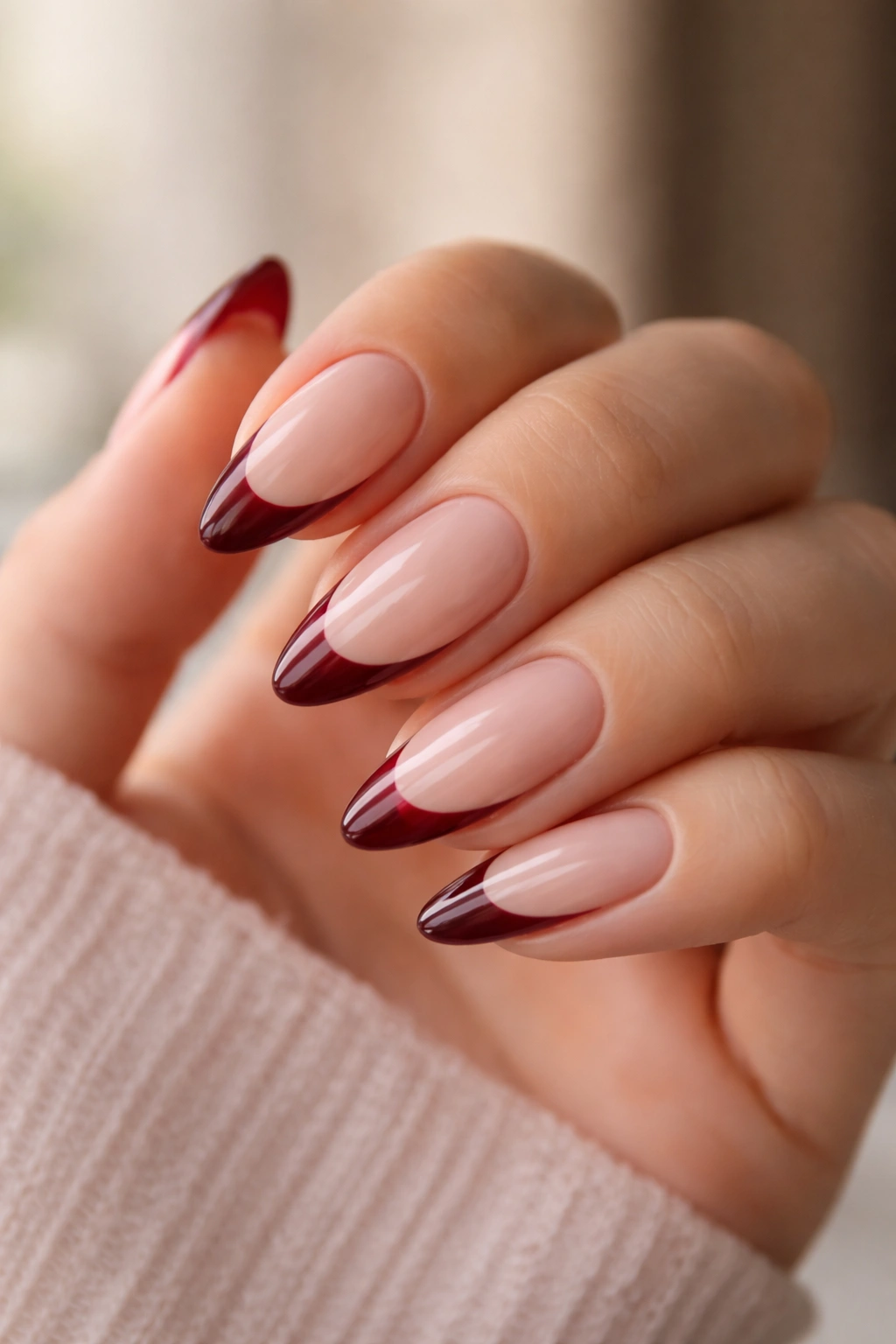 Almond nails with burgundy French tips on a sheer nude base