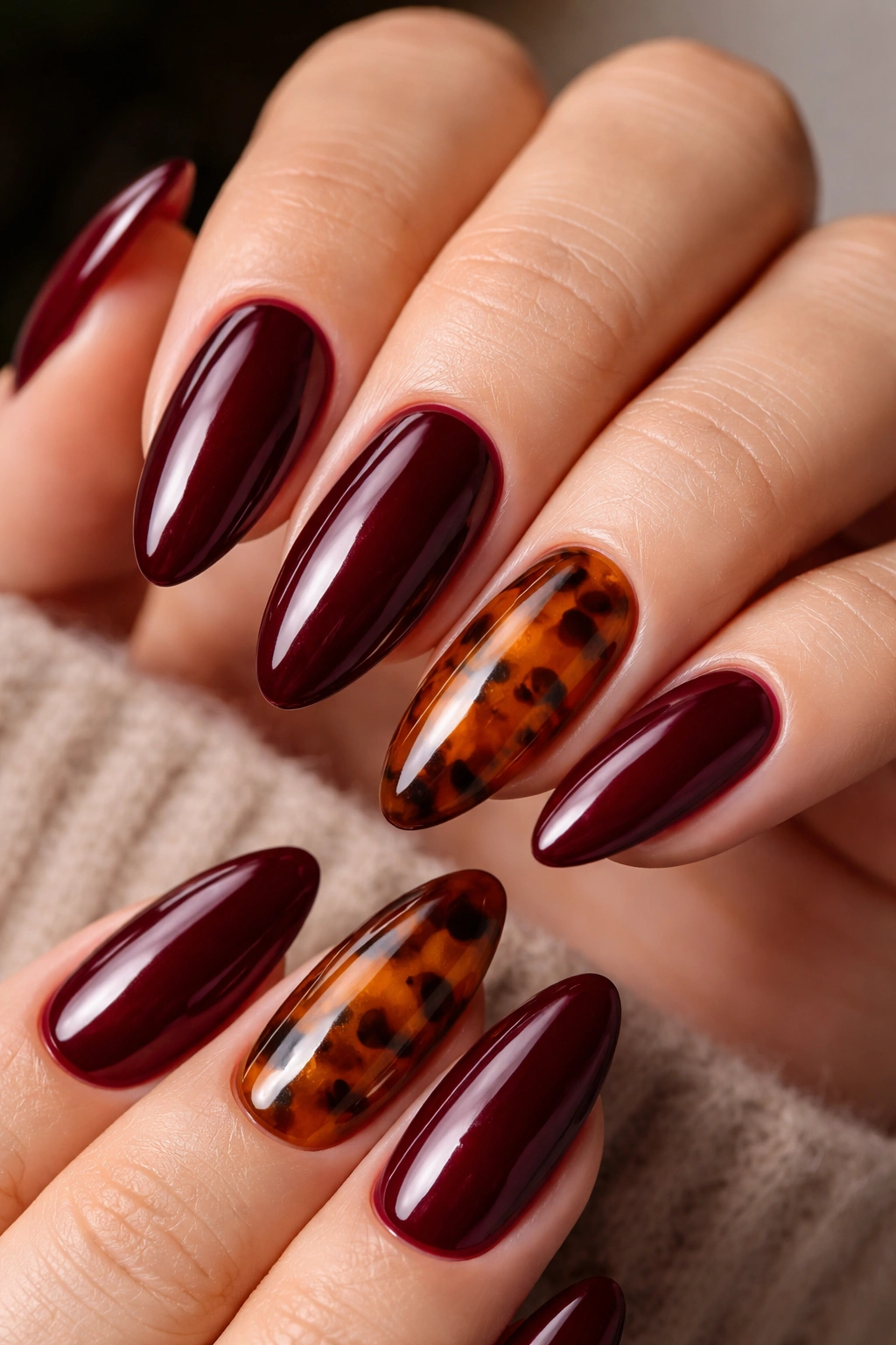 Close-up of burgundy nails with tortoiseshell accent nails on almond shape