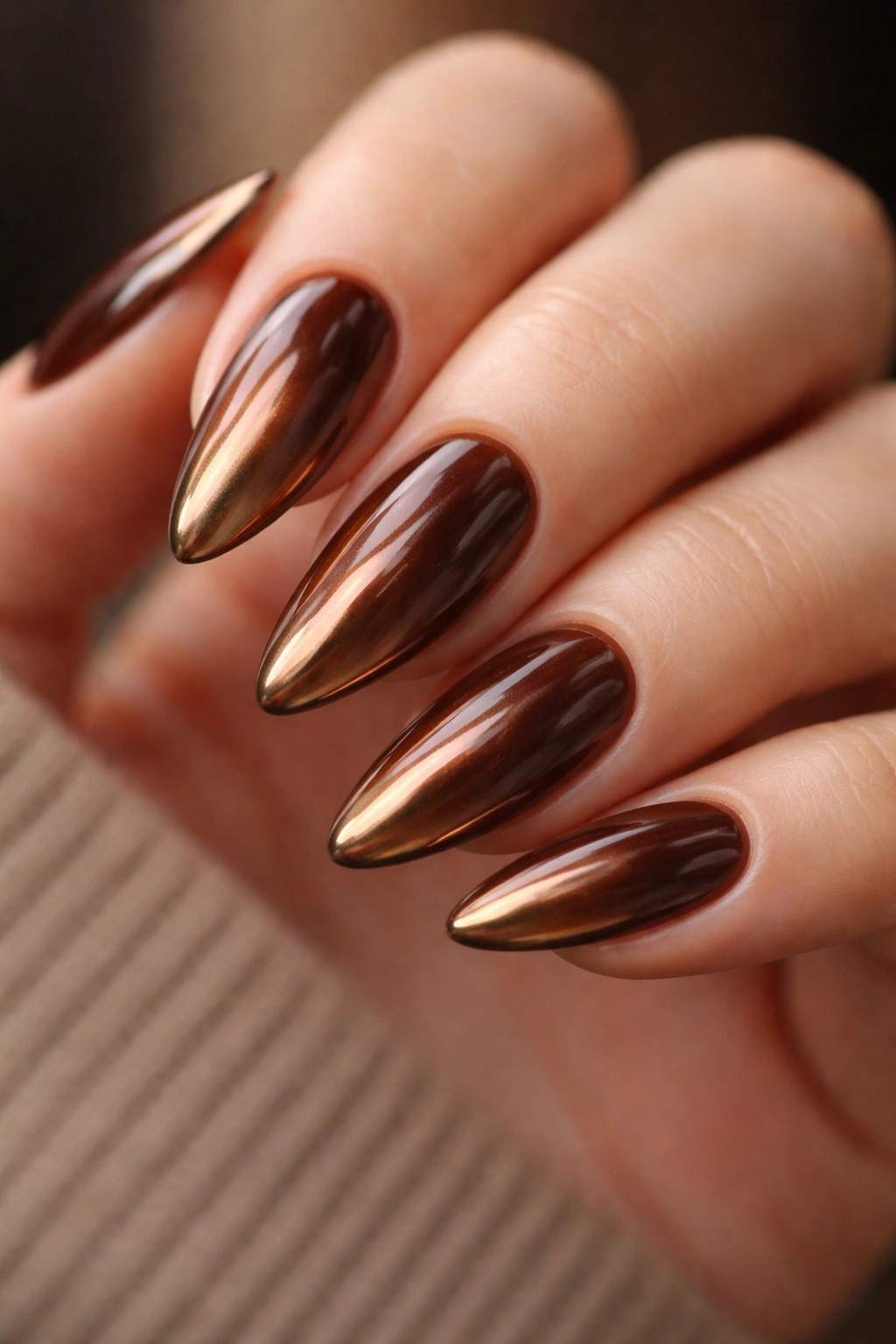 Almond nails with warm brown base and bronze chrome finish