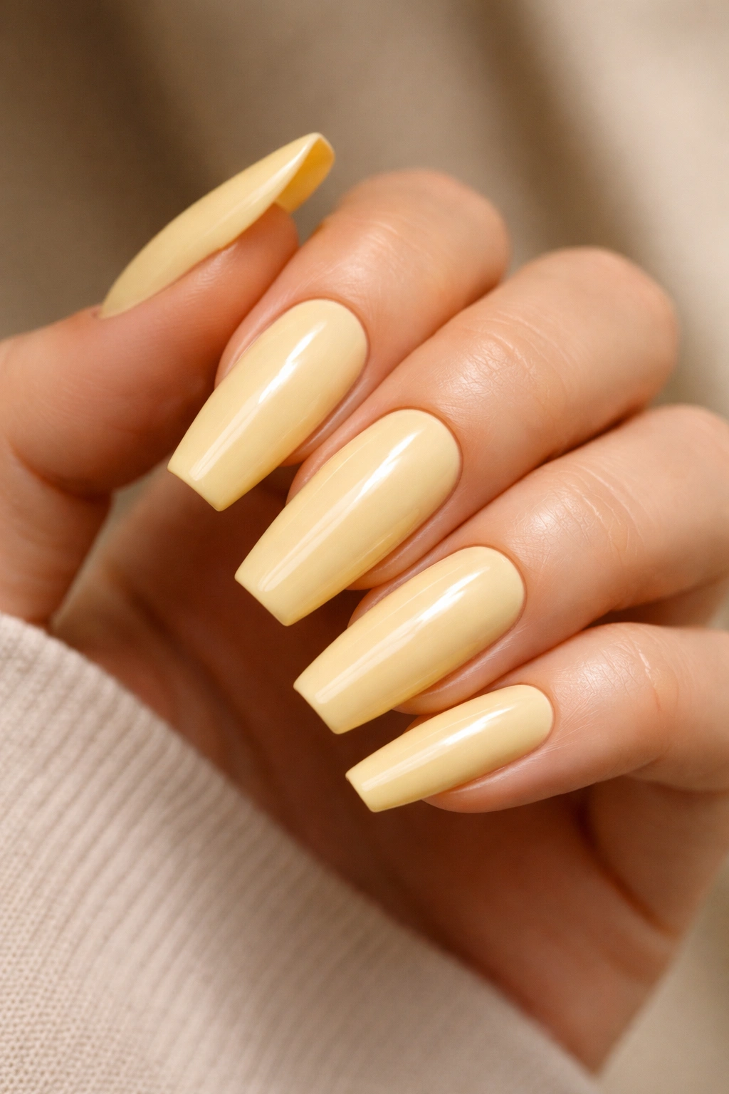 Butter yellow glossy coffin nails on a hand