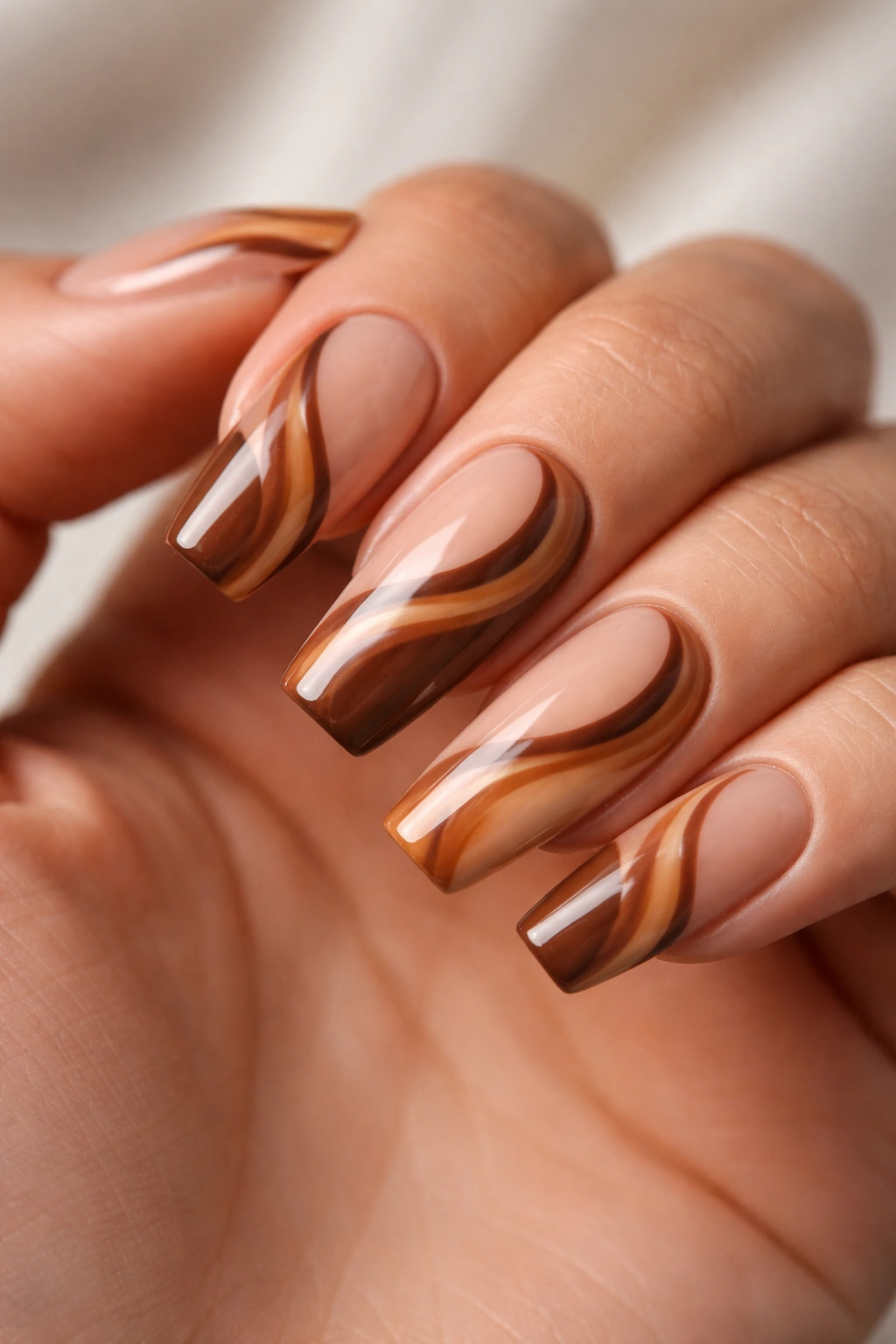 Medium coffin nails with caramel swirl patterns on a nude base