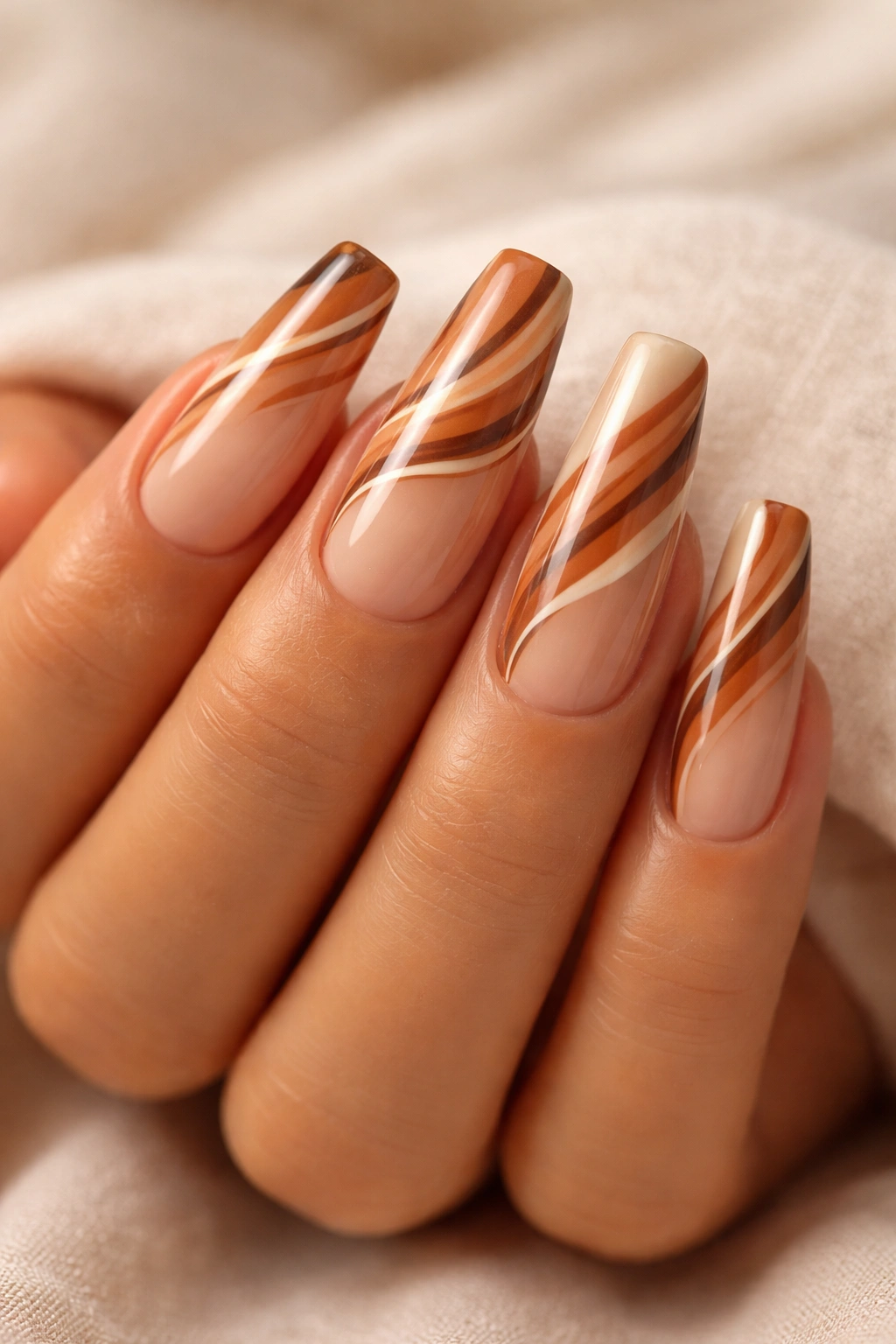 Close-up of coffin nails with caramel swirls on a translucent nude base