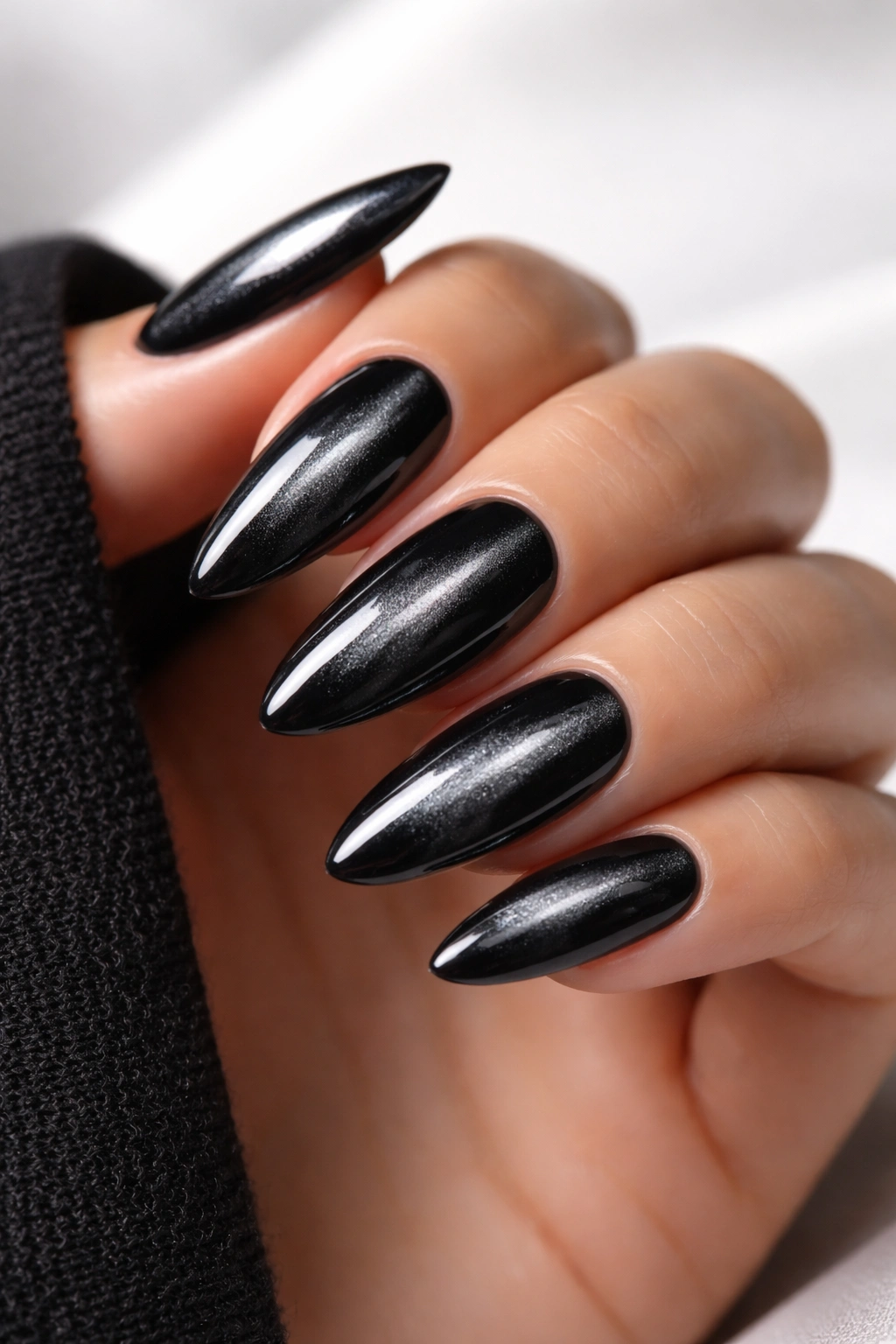 Close-up of black velvet cat eye nails with centered silver shimmer on almond nails