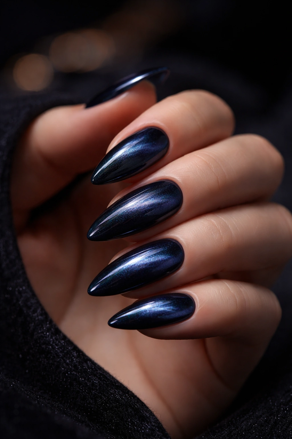 Close-up of velvet cat-eye almond nails in deep navy with shifting shimmer.