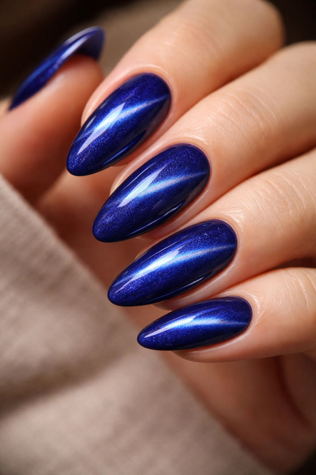 Almond nails with velvet blue cat-eye shimmer along a curved line