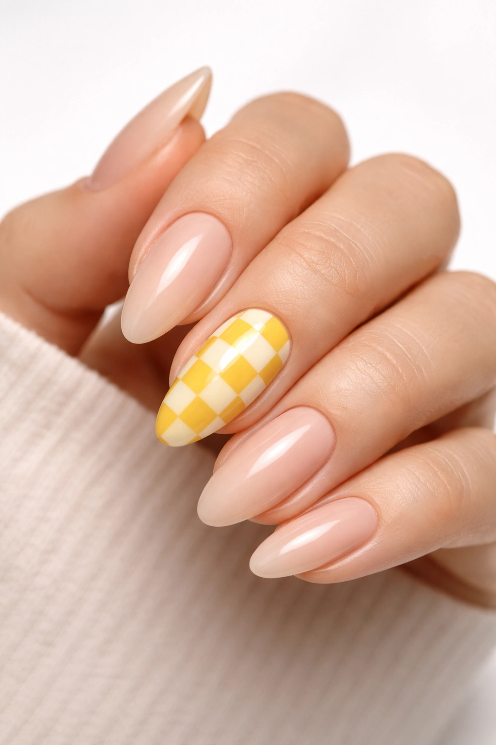 Almond nails with a yellow and white checkerboard accent on one nail