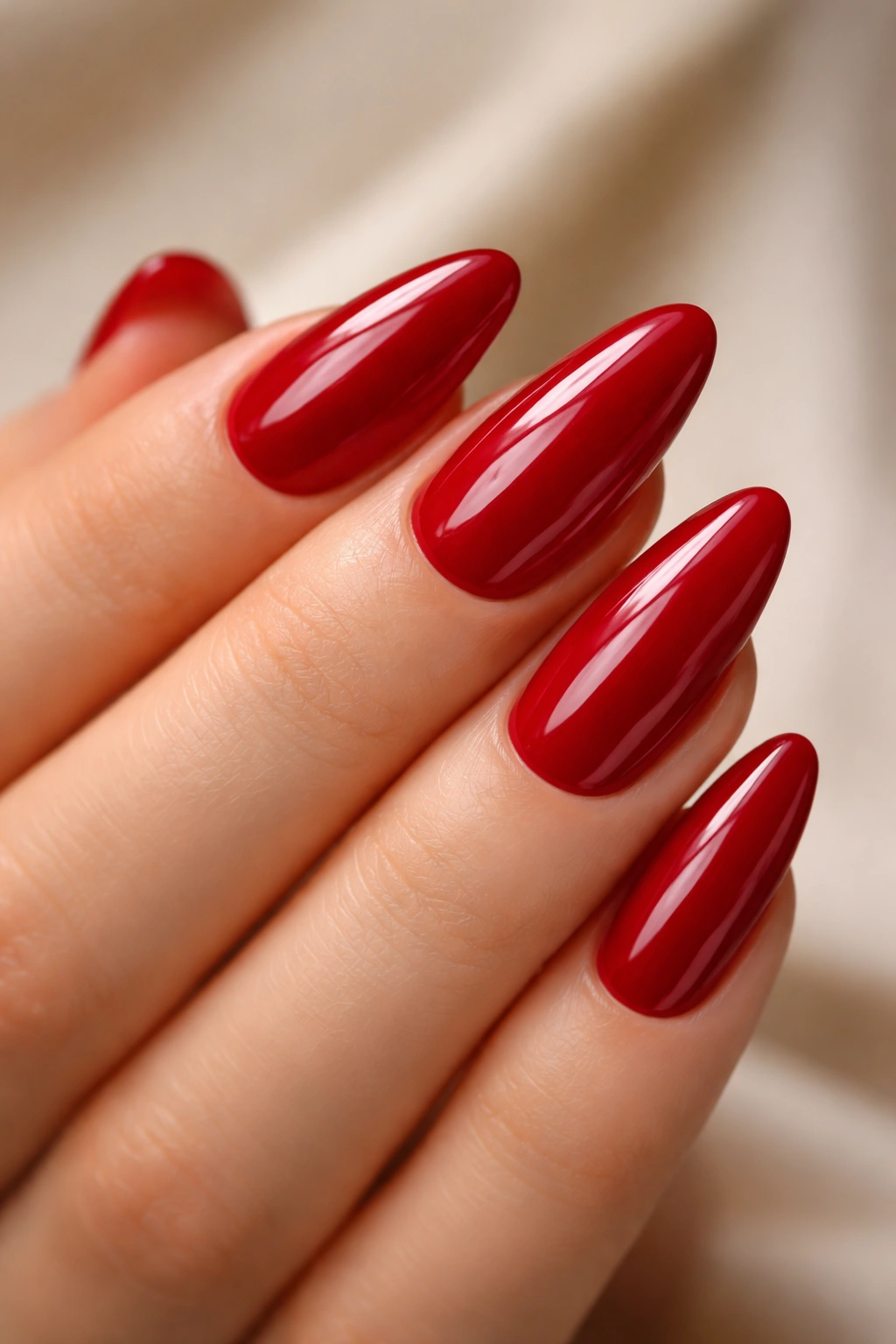 Close-up of cherry red almond nails on gel extensions with glossy finish