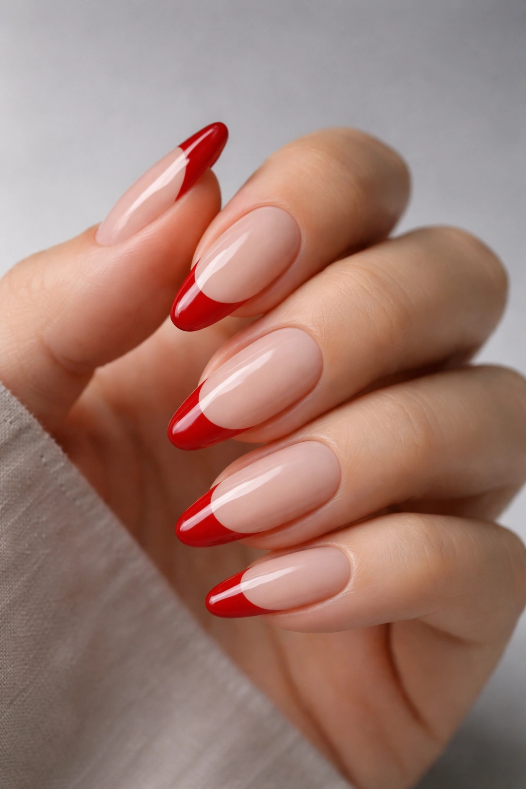 Close-up of almond nails with cherry red French tips on a beige base