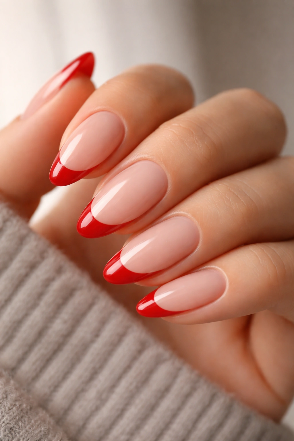 Close-up of cherry red French tips on almond nails with sheer base