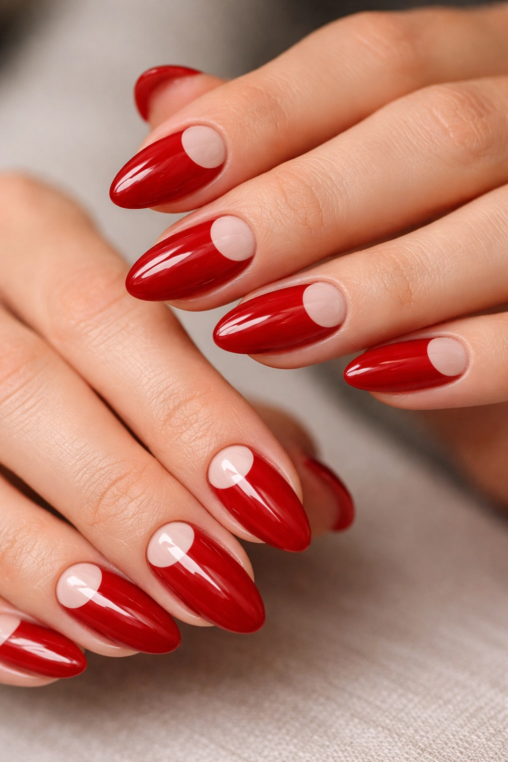 Almond nails with cherry red half-moon design and nude base
