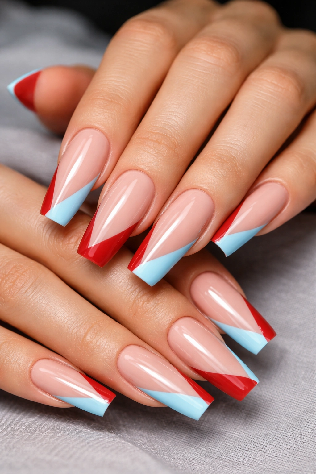Coffin nails with diagonal cherry red and sky blue side-swept tips on a nude base.