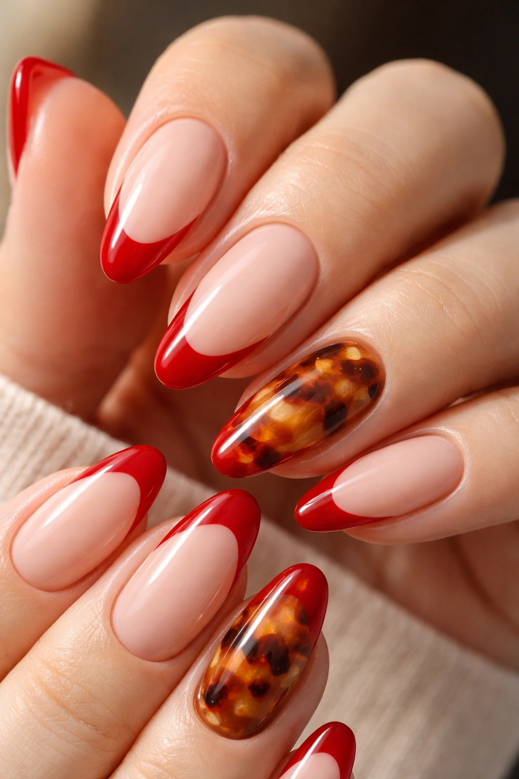 Almond nails with cherry red French tips and tortoiseshell accent nail.