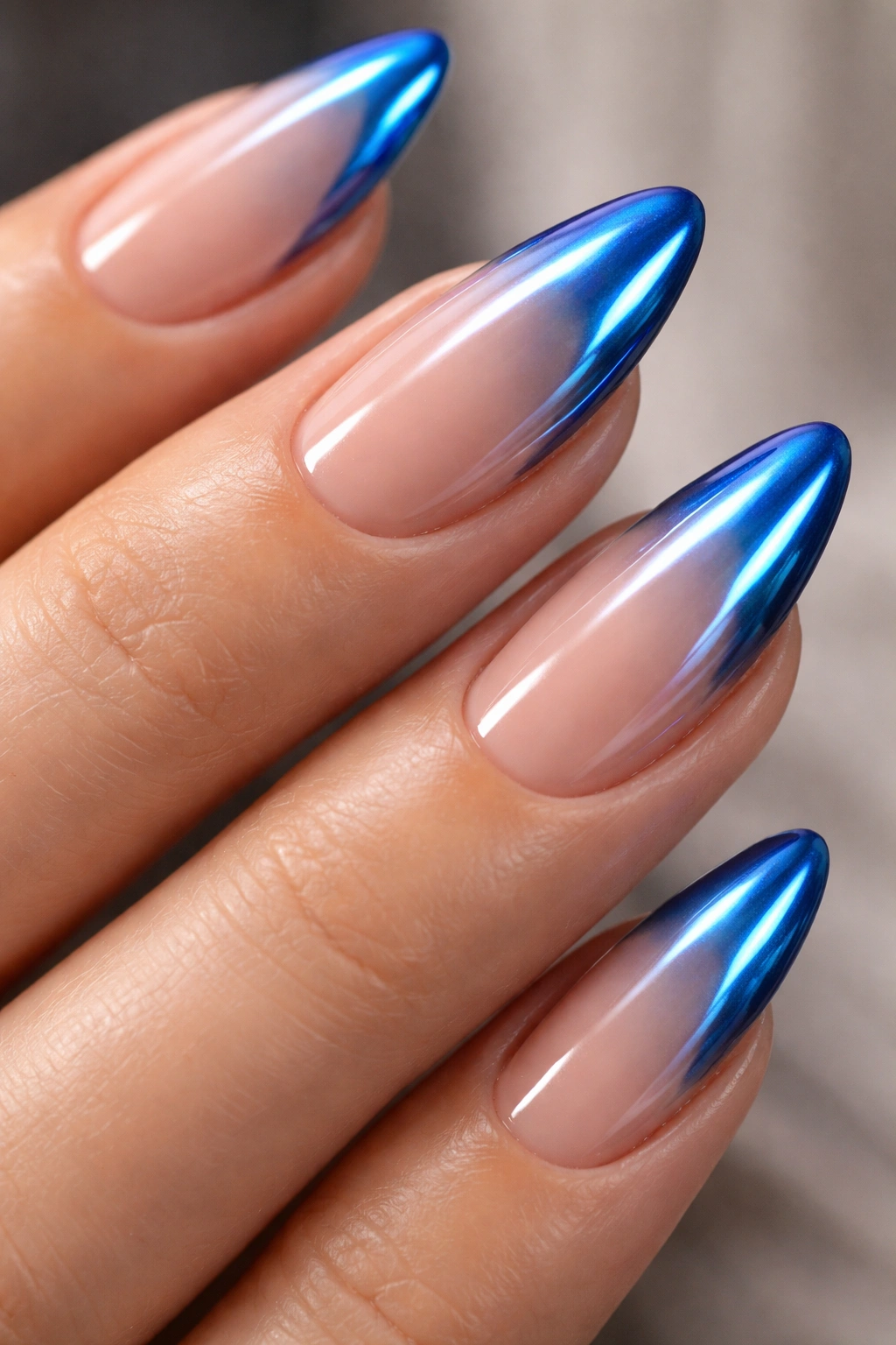 Close-up of almond nails with chrome blue tips and shifting metallic sheen