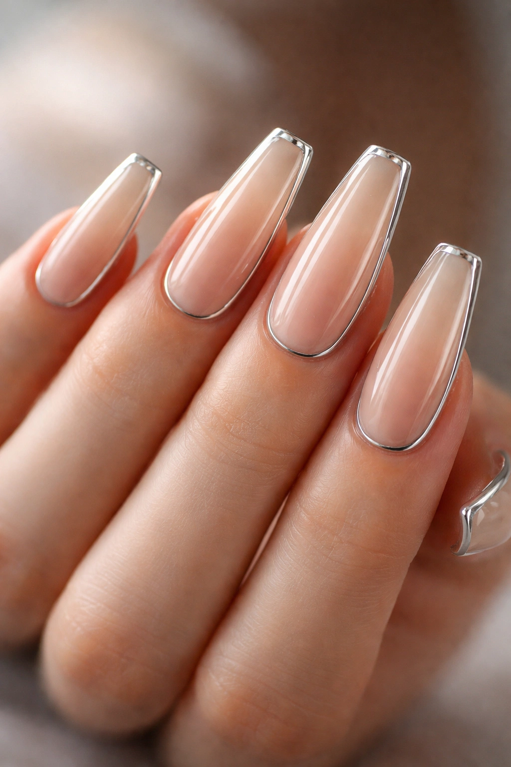 Close-up of nude coffin nails with a thin chrome border outlining the edges