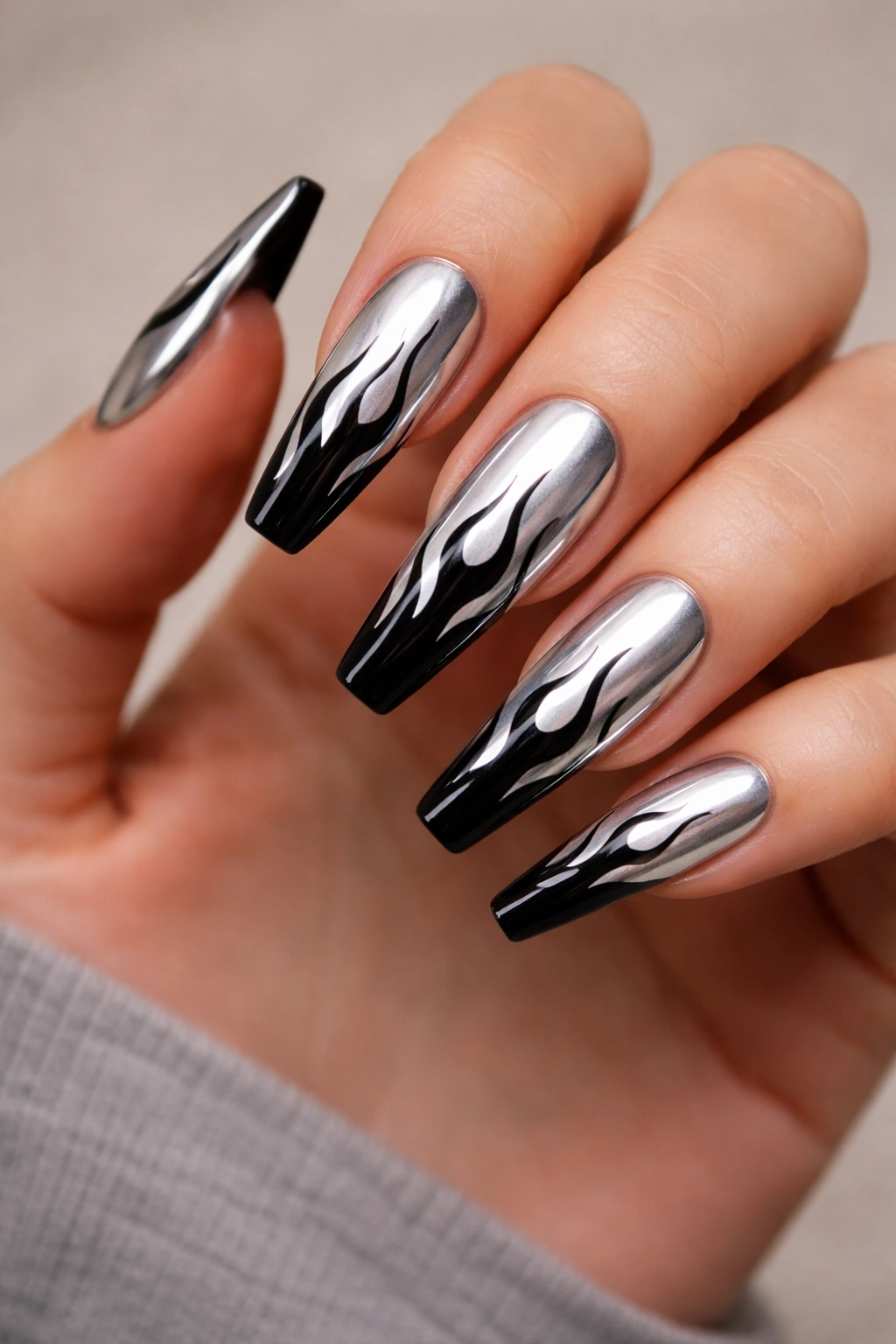 Close-up of coffin nails with silver chrome base and black flame art