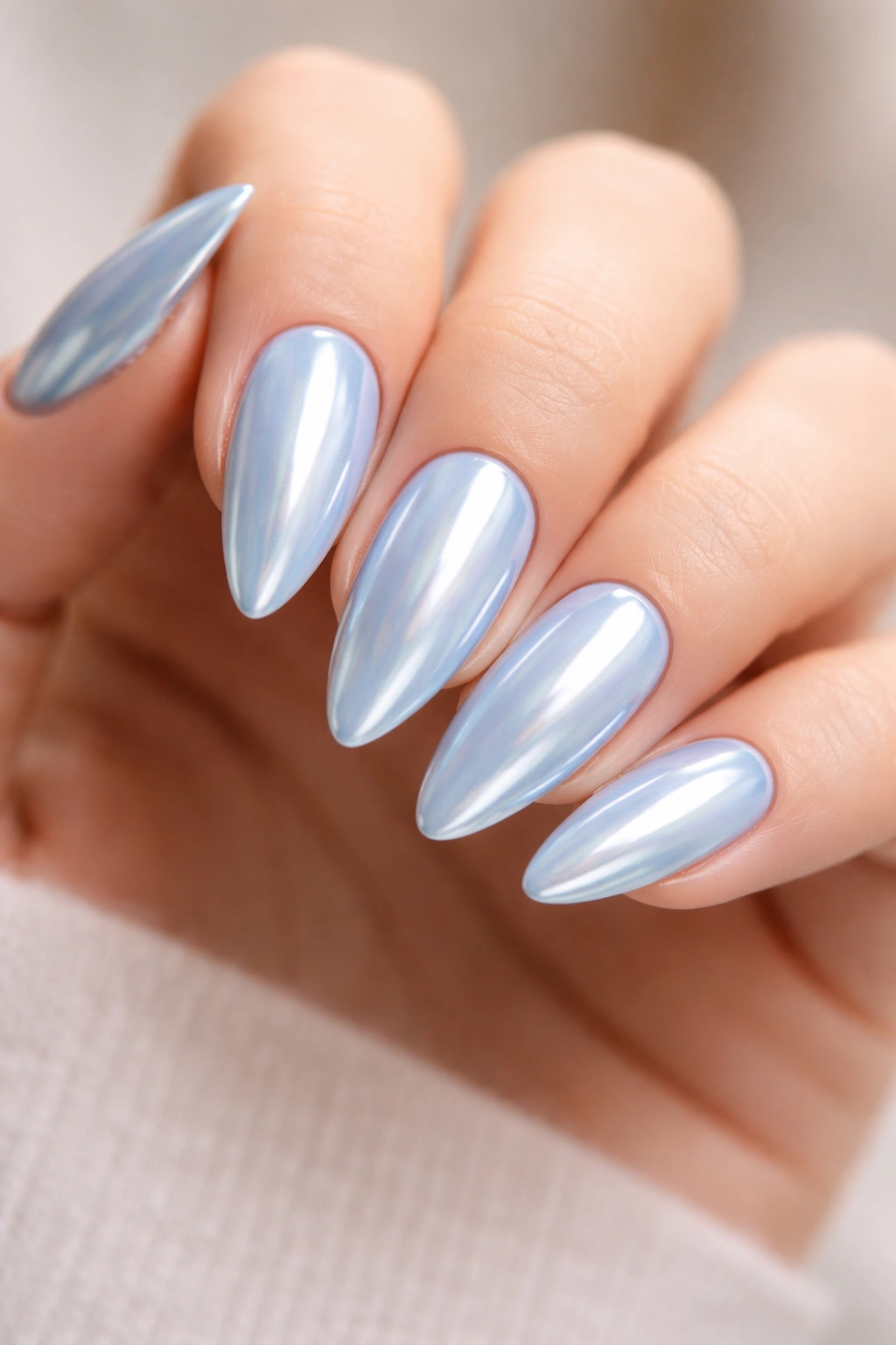 Close-up of almond nails with chrome pastel blue finish