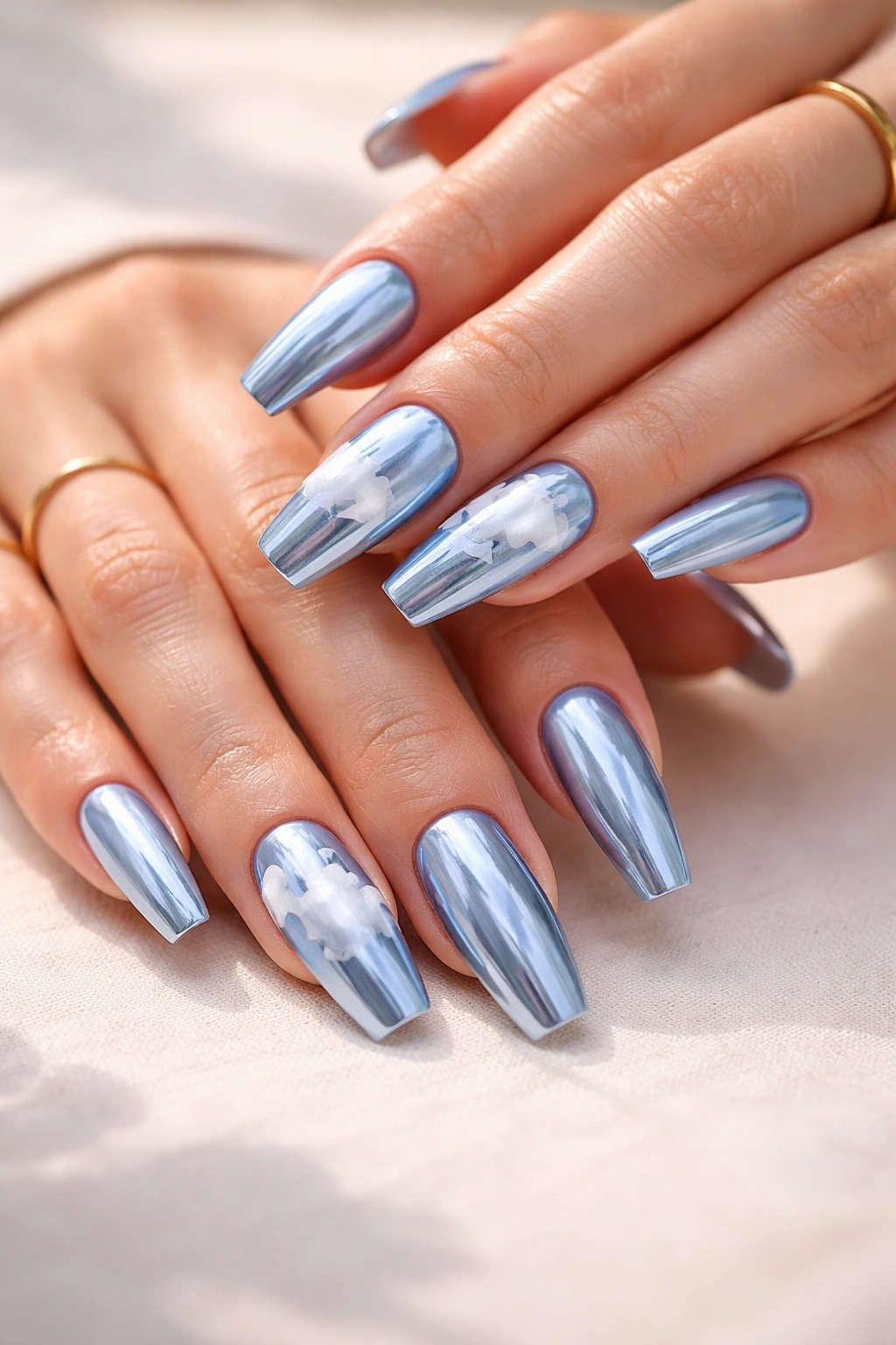 Blue chrome coffin nails with soft white cloud accents on selected nails