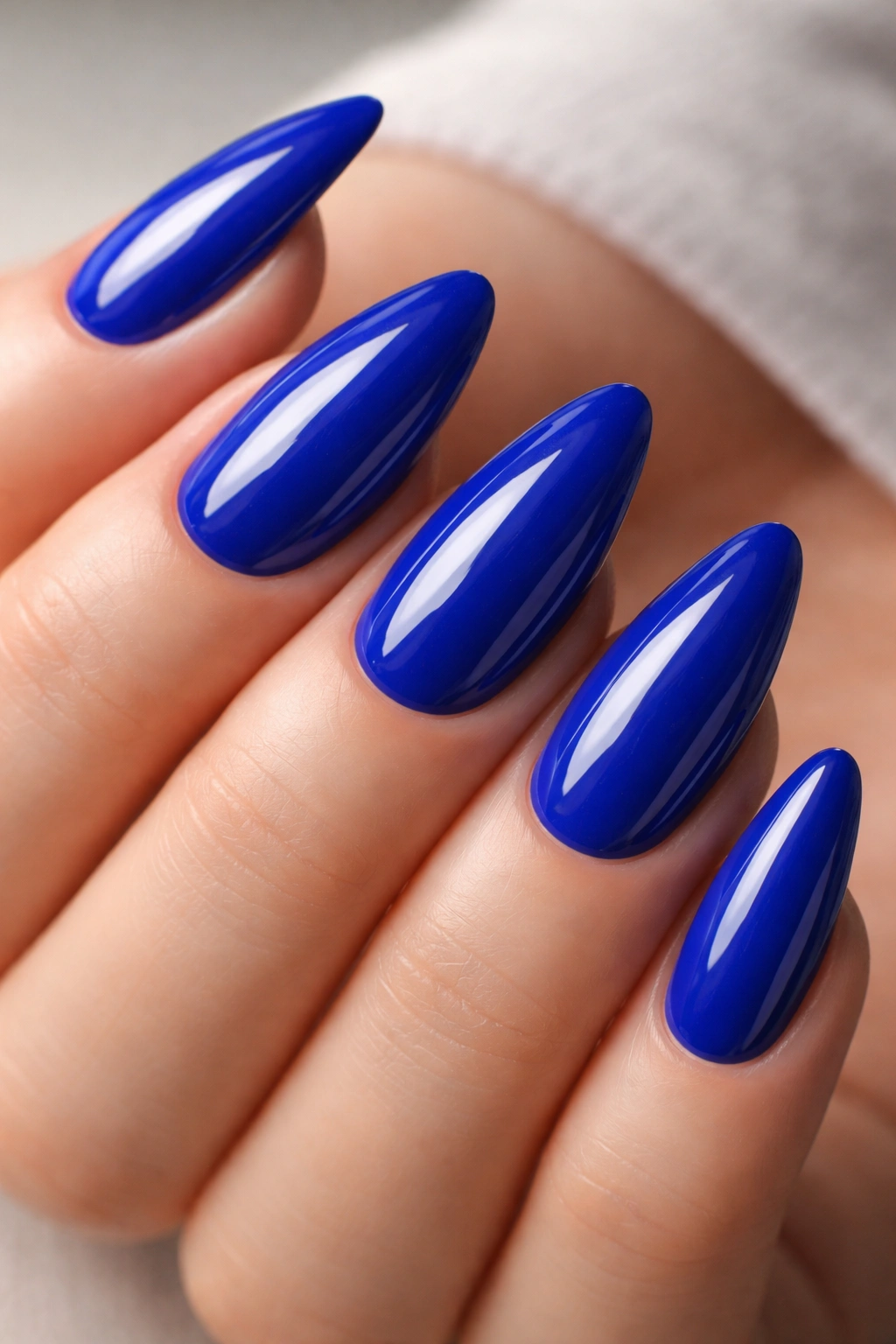 Close-up of cobalt blue almond nails with a glassy finish